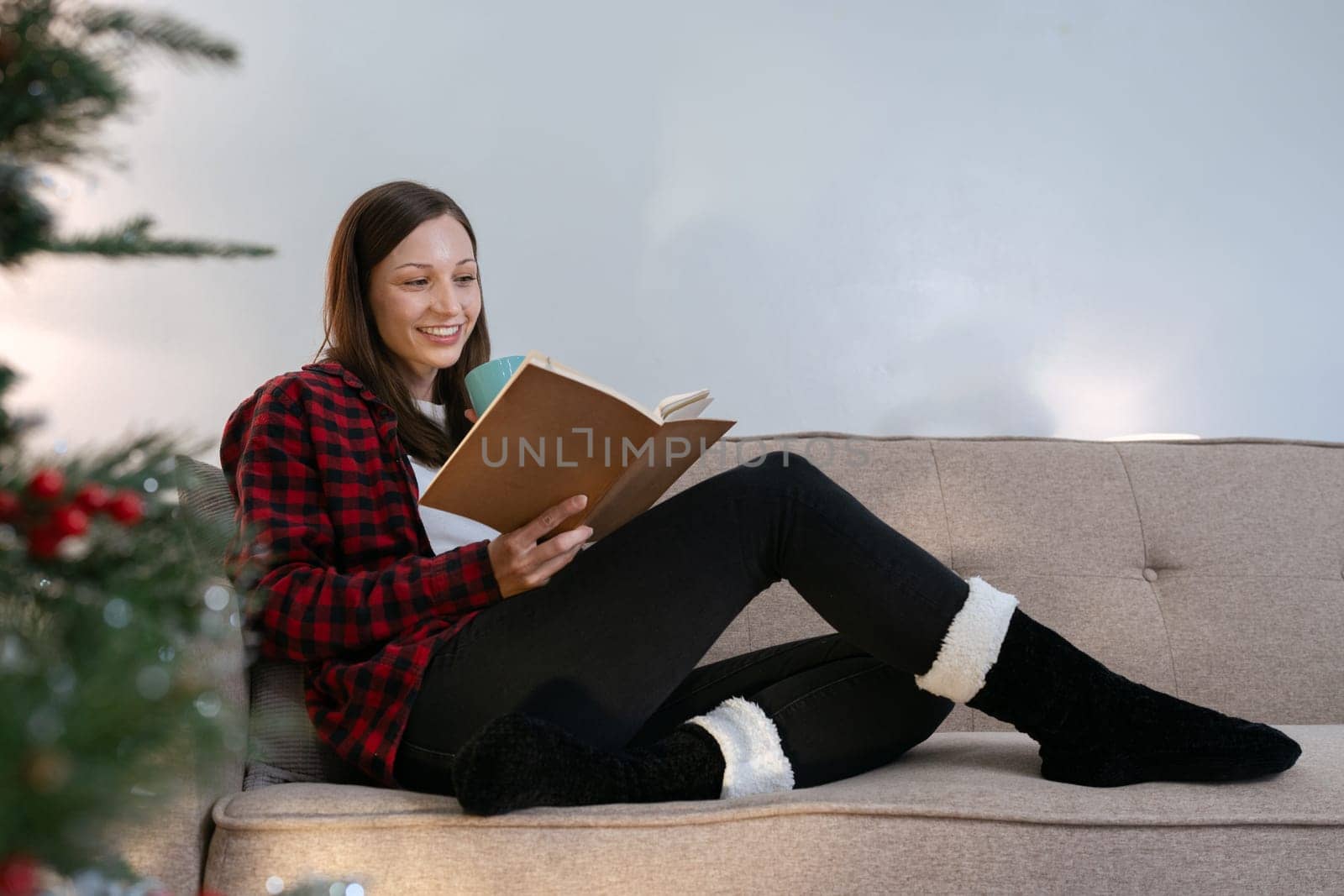 Caucasian woman reading book and relaxation on couch on Christmas holiday by itchaznong