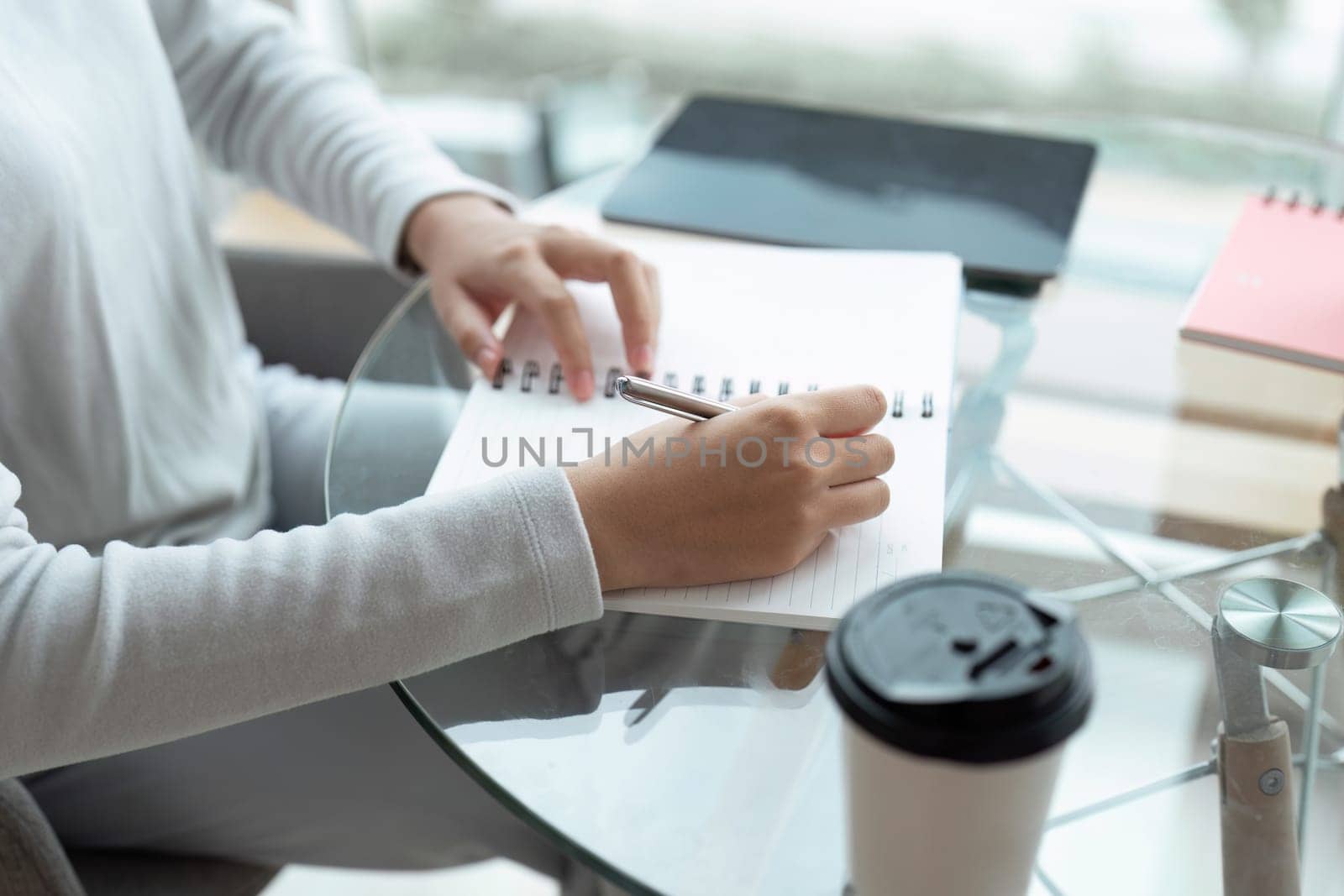 Write daily list before start each day. hands of businesswoman writing in her notebook while working at desk by itchaznong