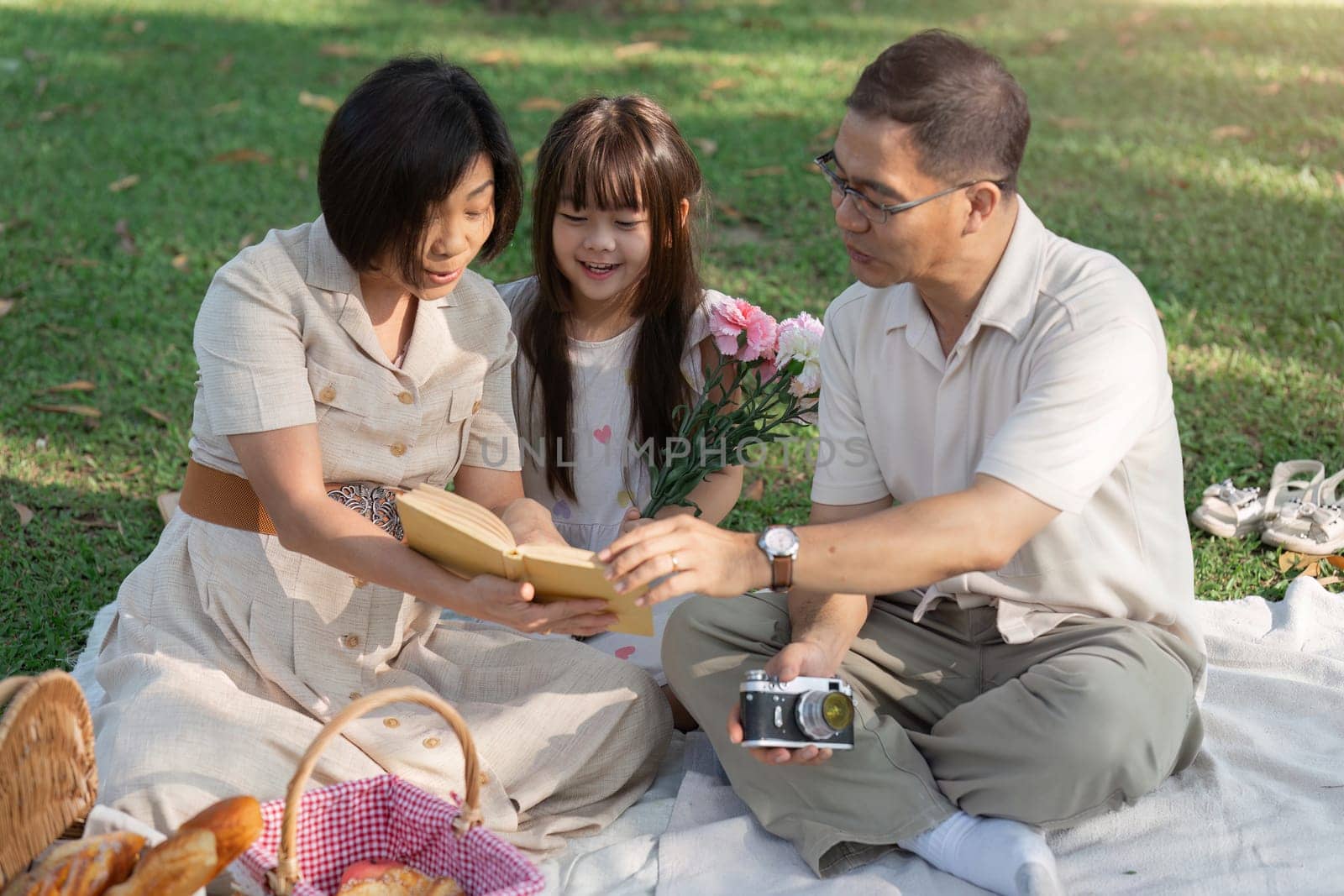 happy smiling family grandparent and grandchild picnic together outside at park.