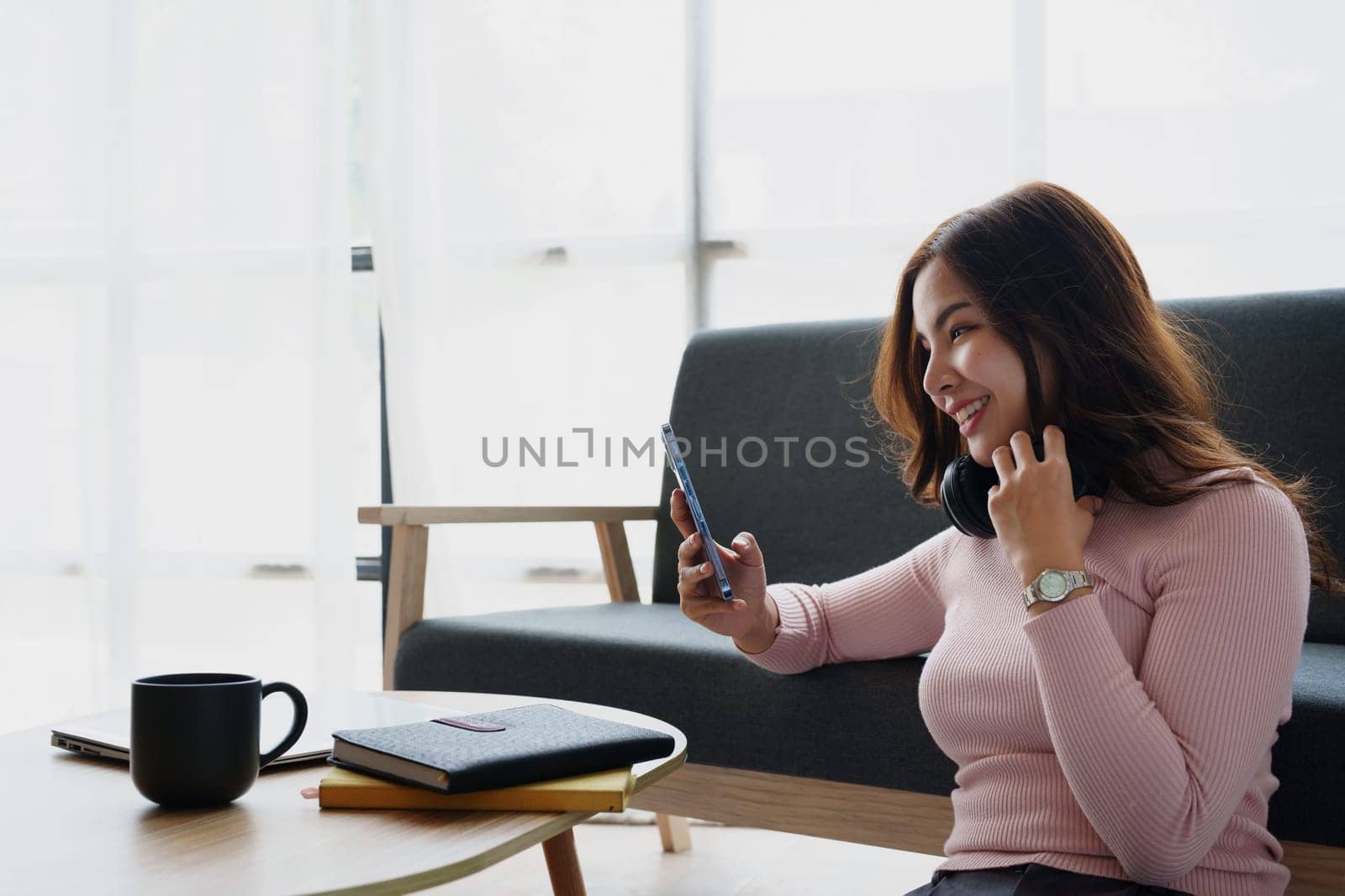 Happy girl checking social media holding smartphone sitting at sofa in living room at home relaxing concepts by Manastrong