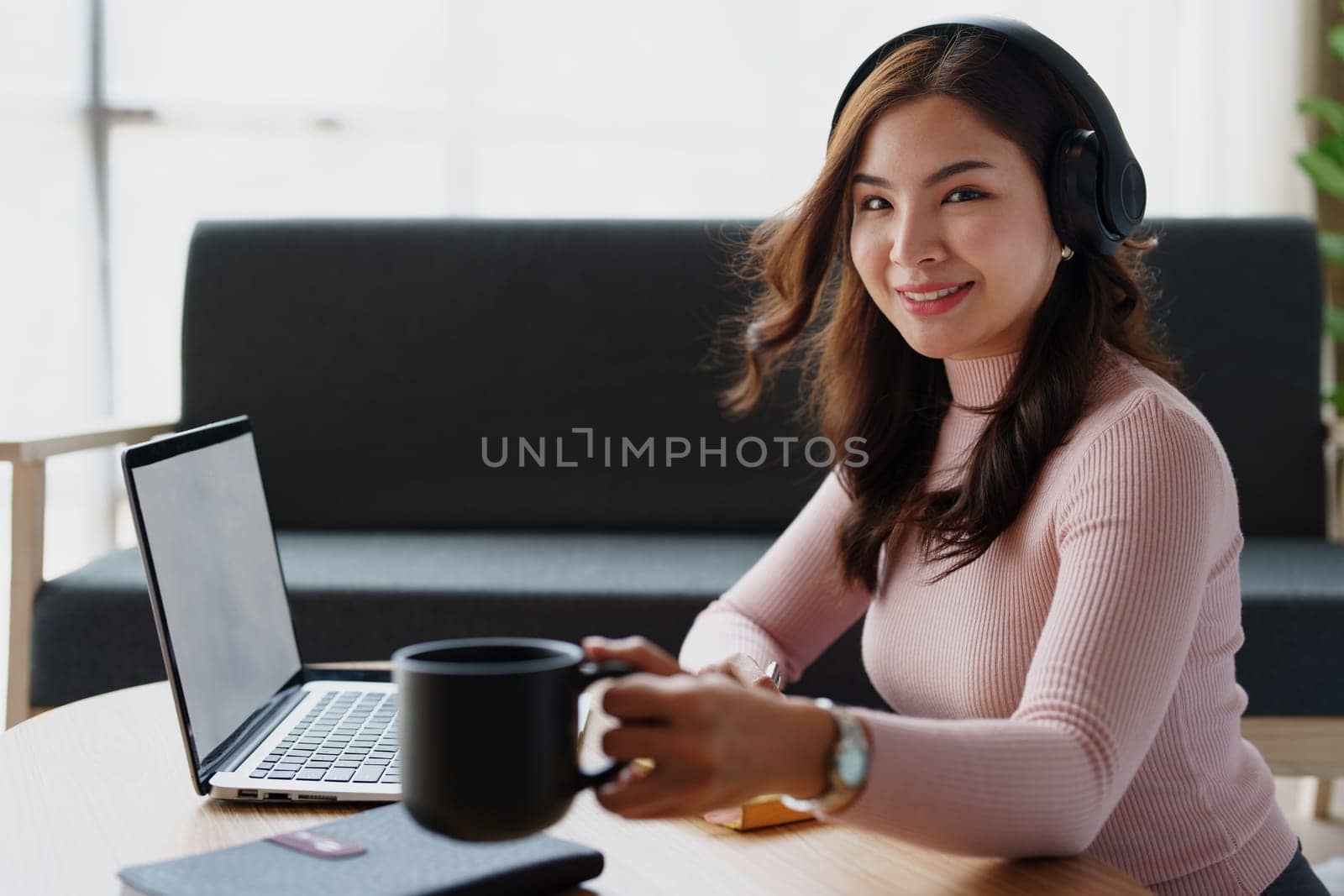 Woman relaxing wearing headphones and drinking coffee at home. by Manastrong