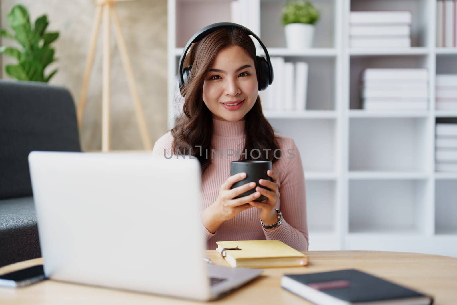 Woman relaxing wearing headphones and drinking coffee at home. by Manastrong