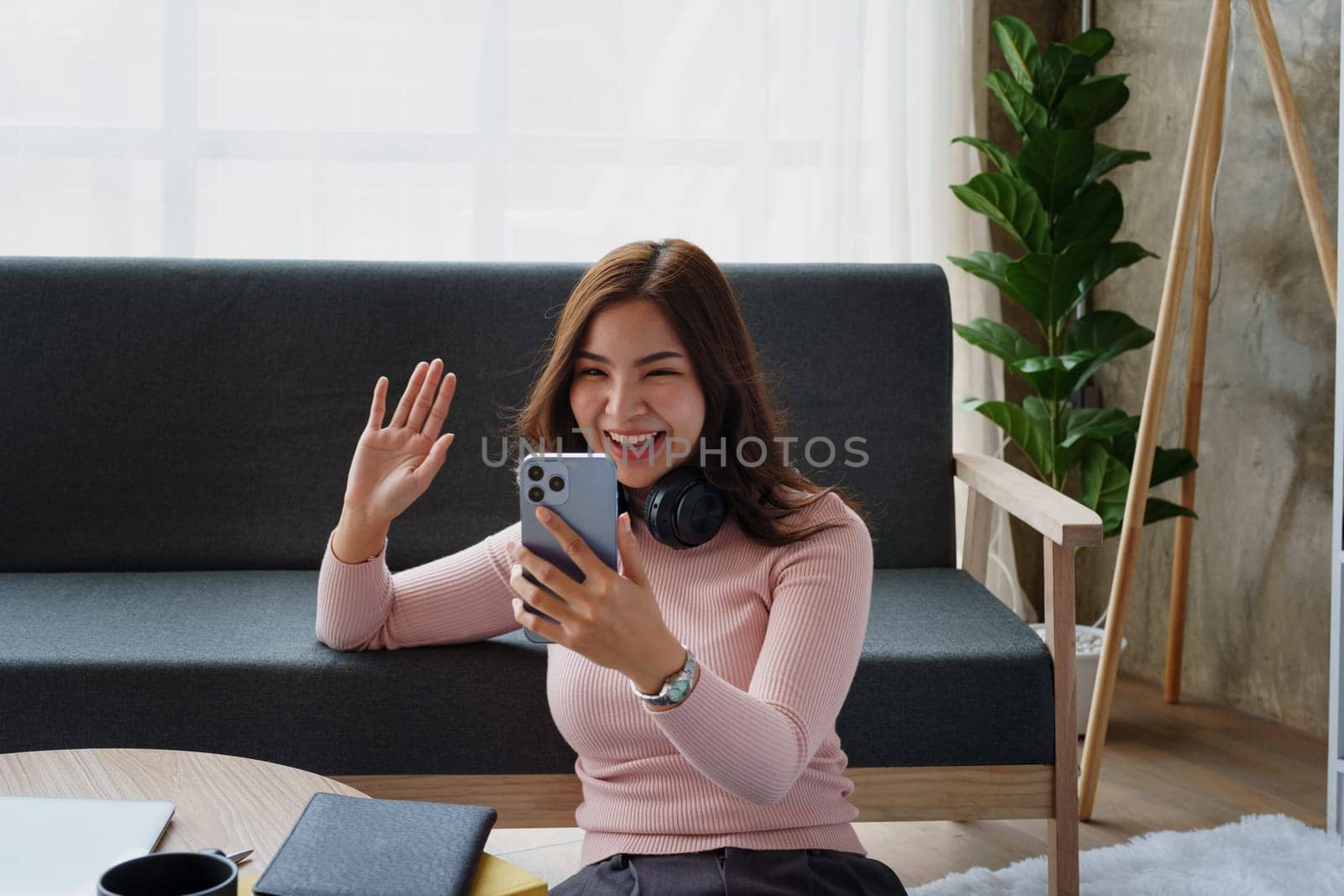 Happy girl checking social media holding smartphone sitting at sofa in living room at home relaxing concepts by Manastrong