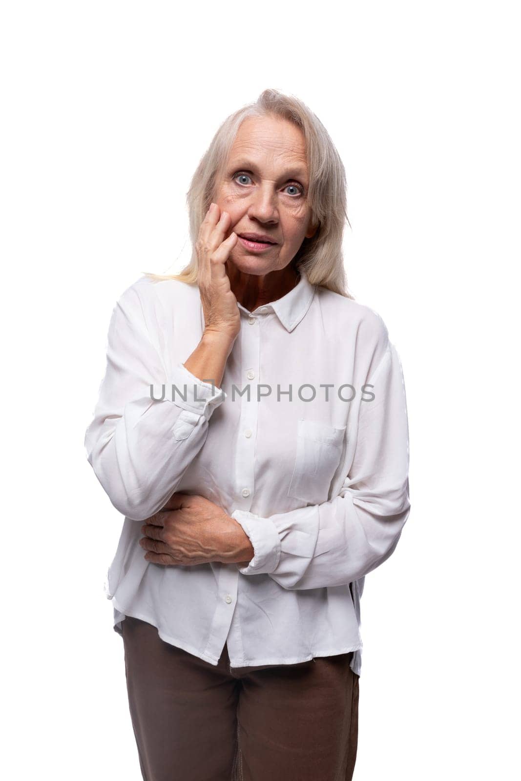 Pensioner woman with gray hair feels suspicious looking at camera.
