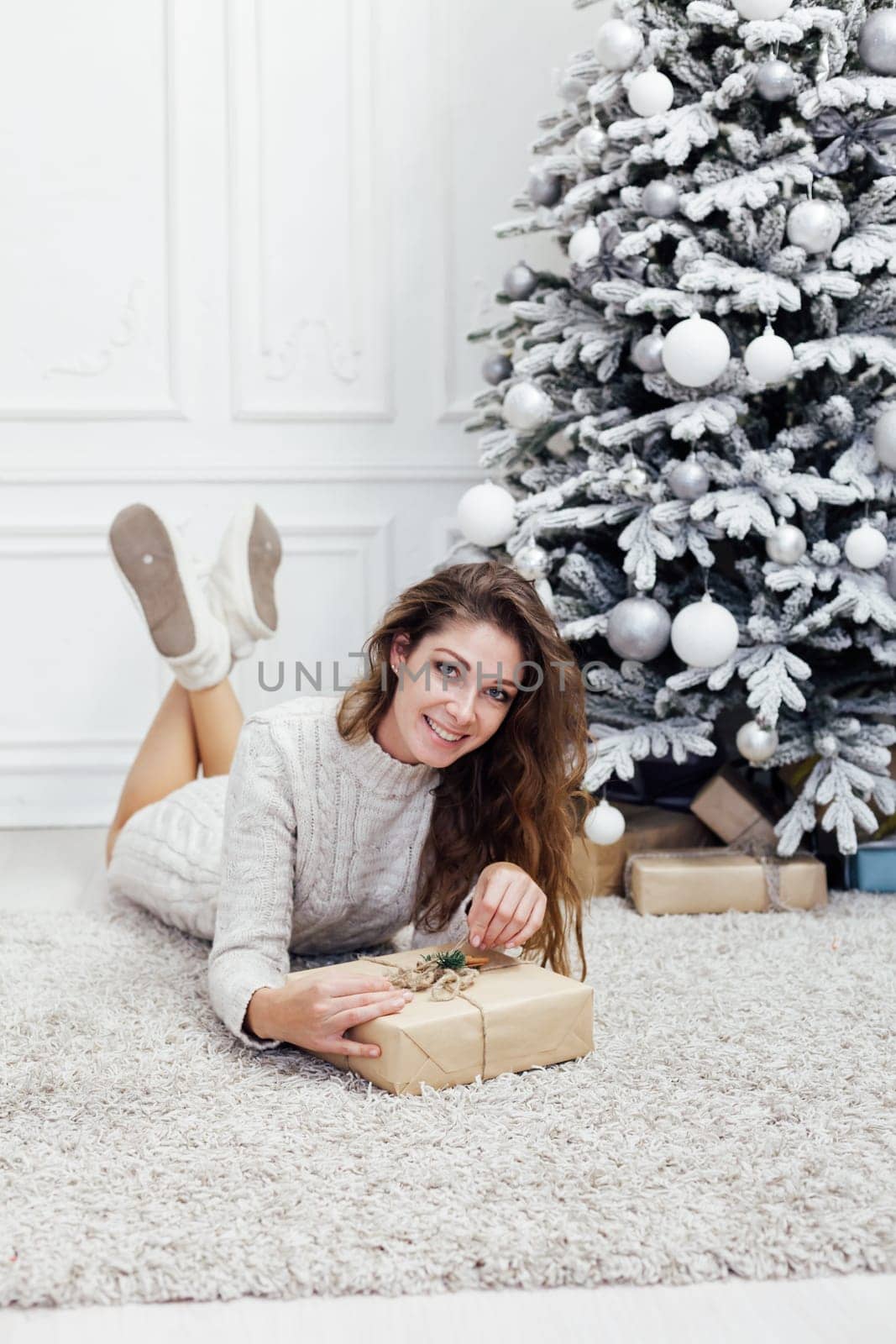 Beautiful woman decorating christmas tree with gifts for new year by Simakov