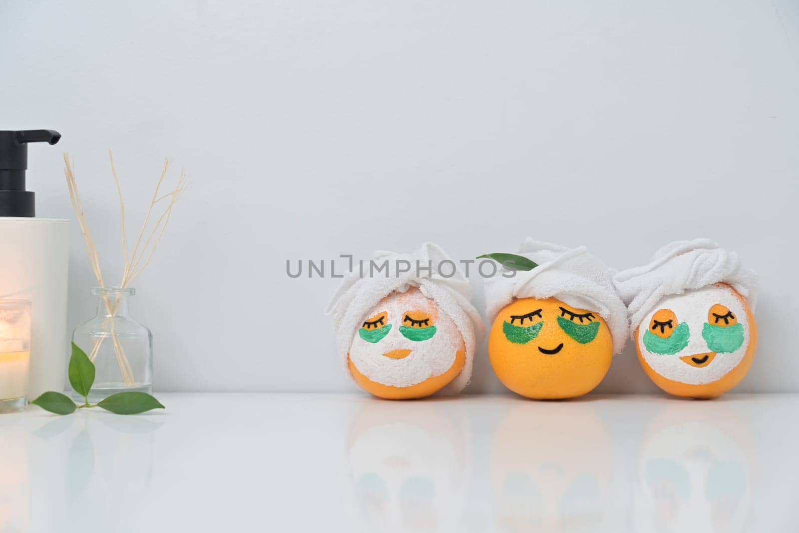 Orange fruits with towel and patches under eyes. Spa treatment and self care concept.