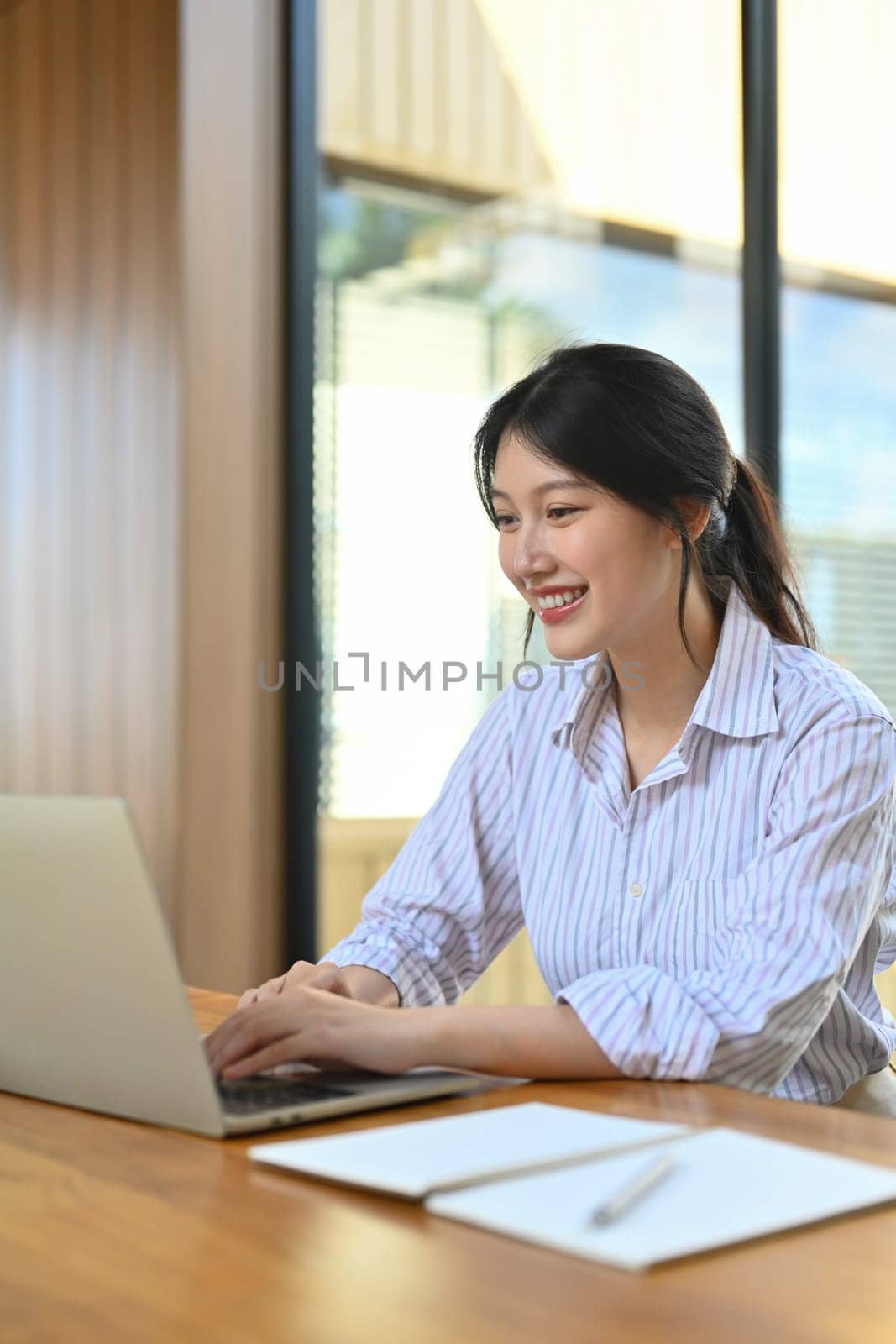 Charming asian female employee checking business email on her laptop computer.