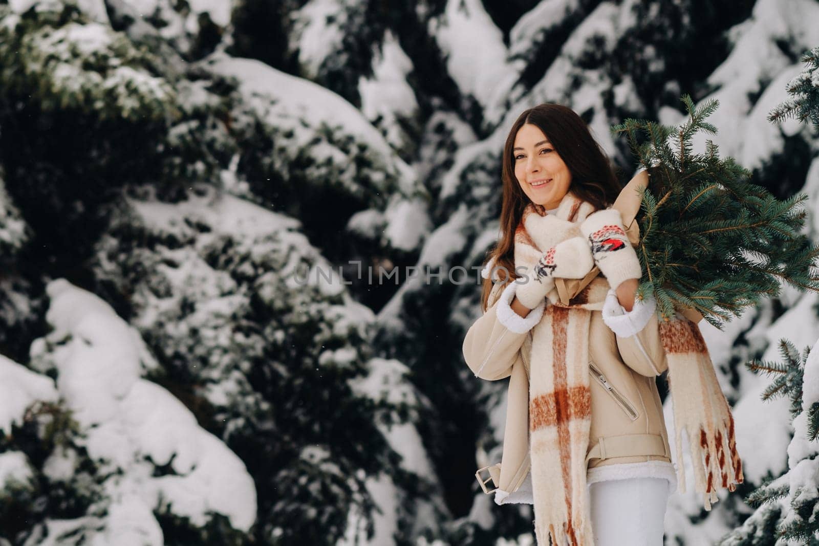 A girl in a winter forest with a bouquet of fir branches. Snowy winter.