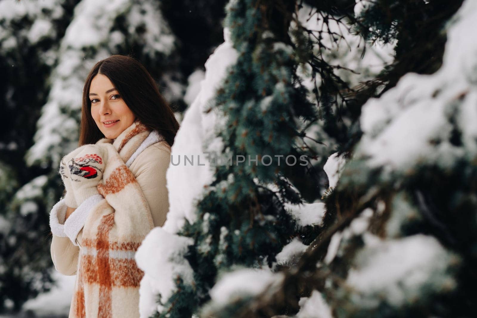 Portrait of a girl with long hair in mittens in a winter forest . Snowy winter.