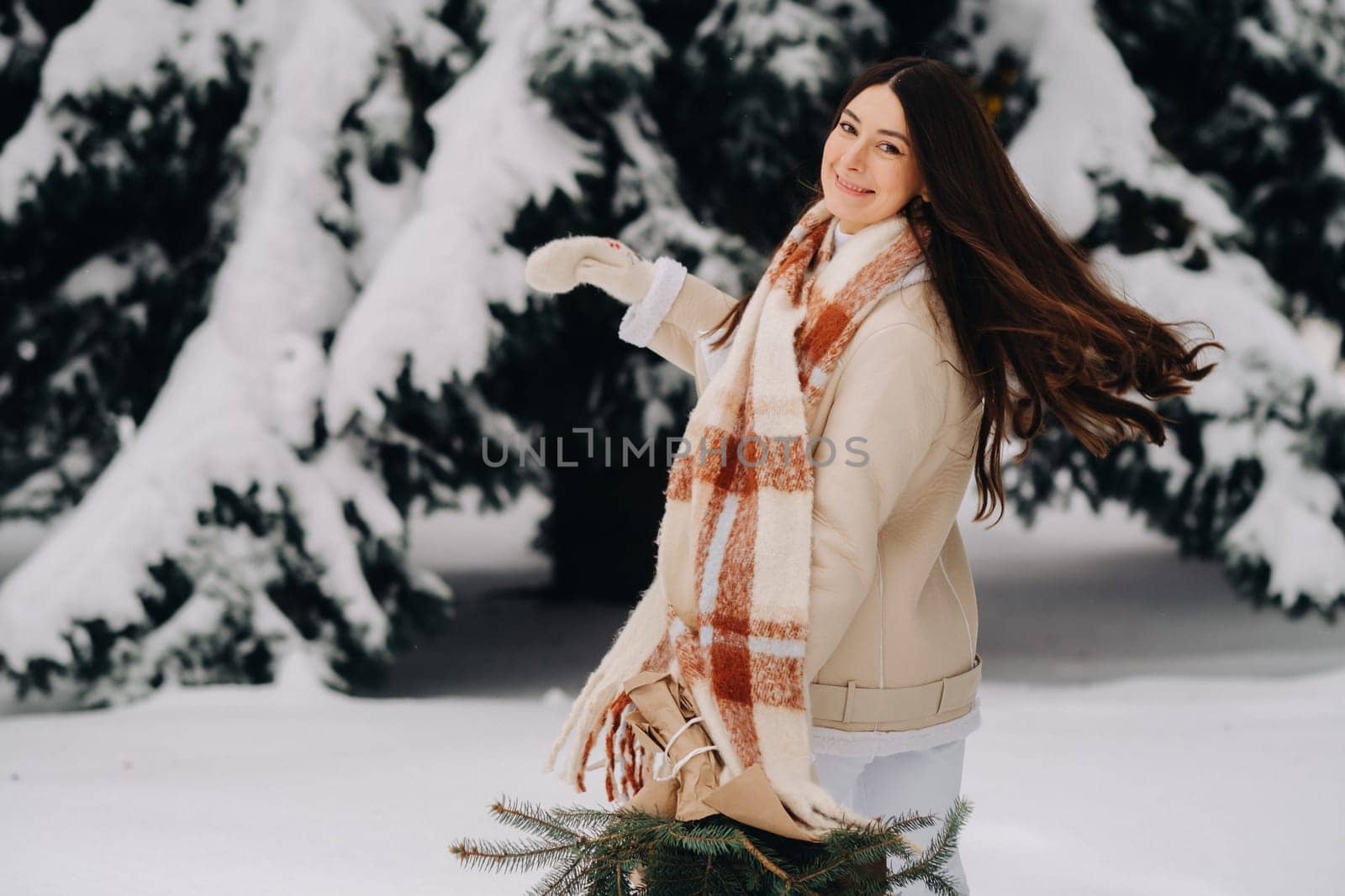 A girl in a winter forest with a bouquet of fir branches. Snowy winter.