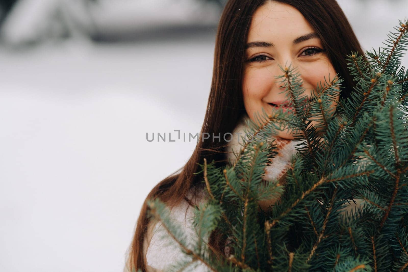 A girl in a winter forest with a bouquet of fir branches. Snowy winter.