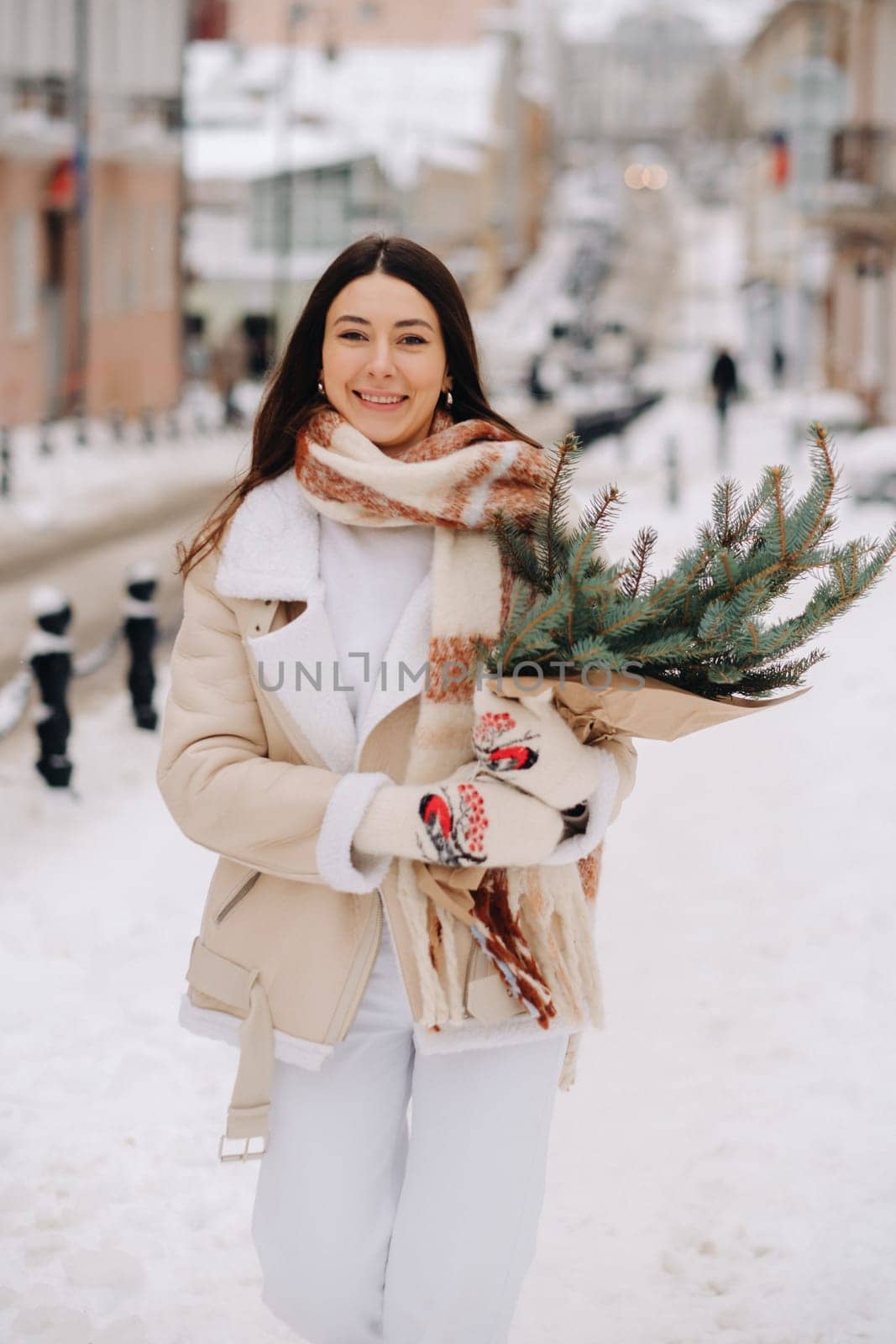 A girl with long hair in winter on the street with a bouquet of fresh fir branches by Lobachad