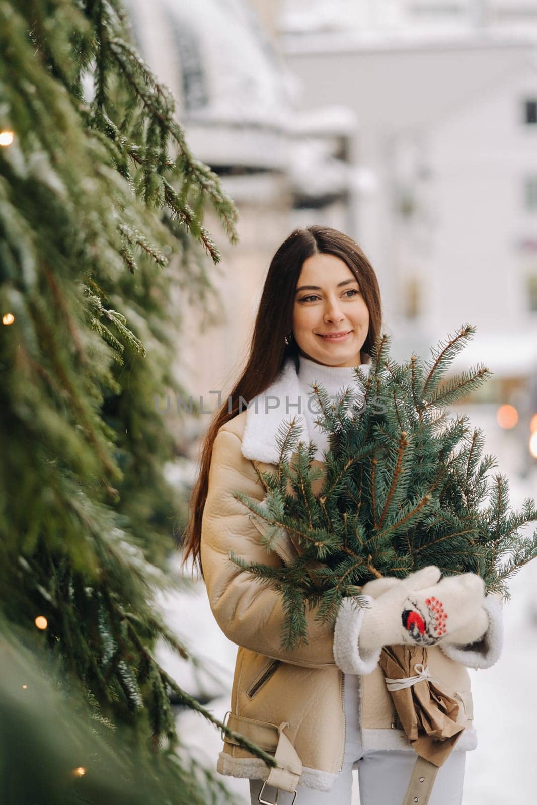 A girl with long hair in winter on the street with a bouquet of fresh fir branches by Lobachad