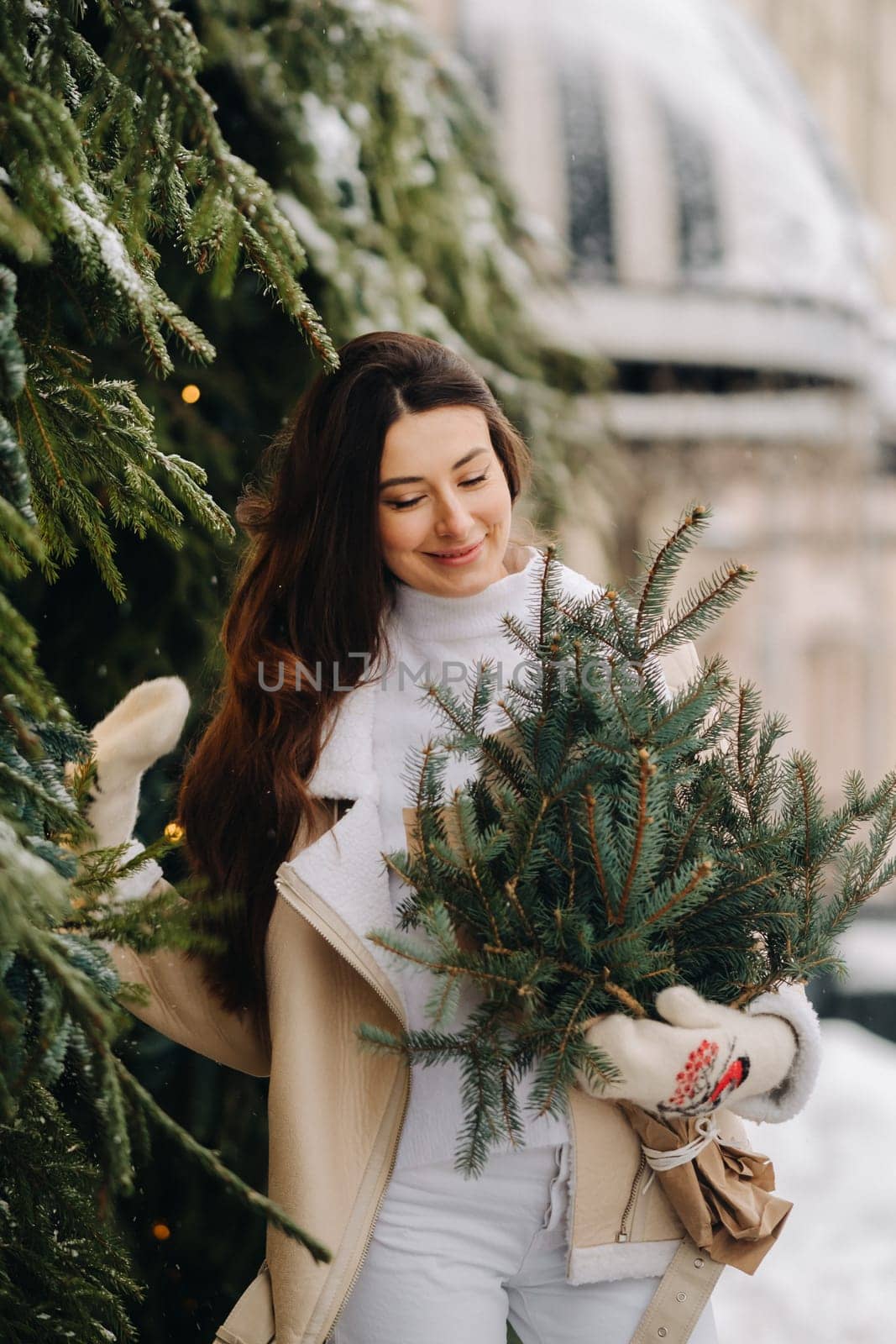 A girl with long hair in winter on the street with a bouquet of fresh fir branches by Lobachad