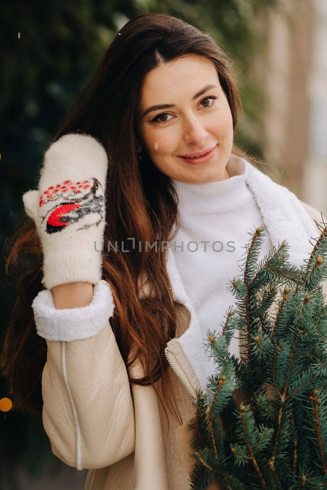 A girl with long hair in winter on the street with a bouquet of fresh fir branches.