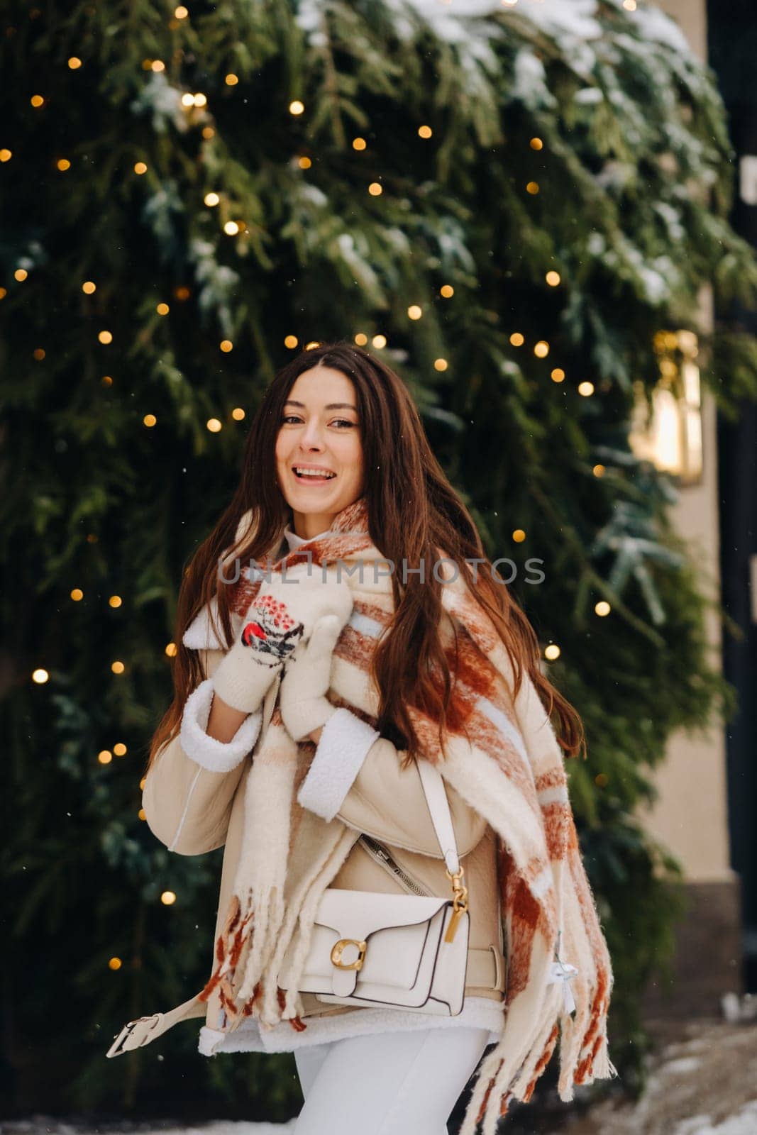 A girl with long hair in a scarf and with a white handbag walks down the street in winter by Lobachad