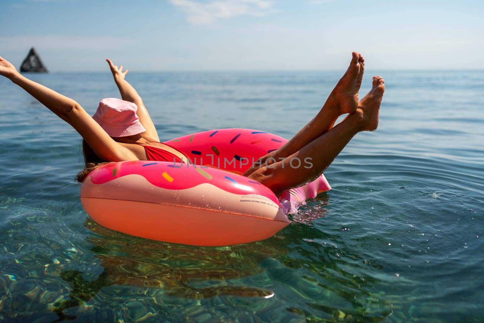 Summer vacation woman in hat floats on an inflatable donut mattress. Happy woman relaxing and enjoying family summer travel holidays travel on the sea