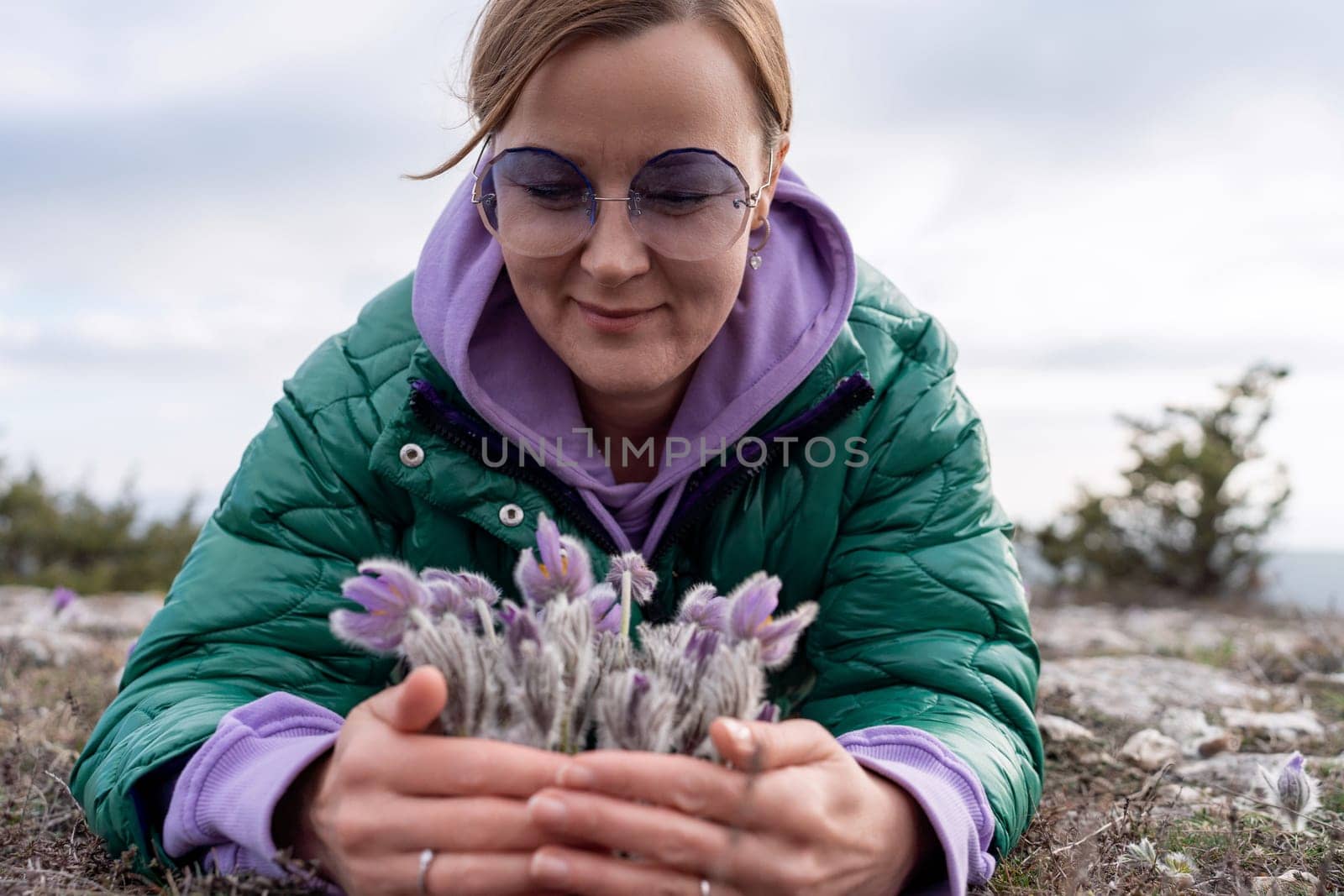 Dream grass woman spring flower. Woman lies on the ground and hugs flowers pasqueflower or Pulsatilla Grandis flowers.