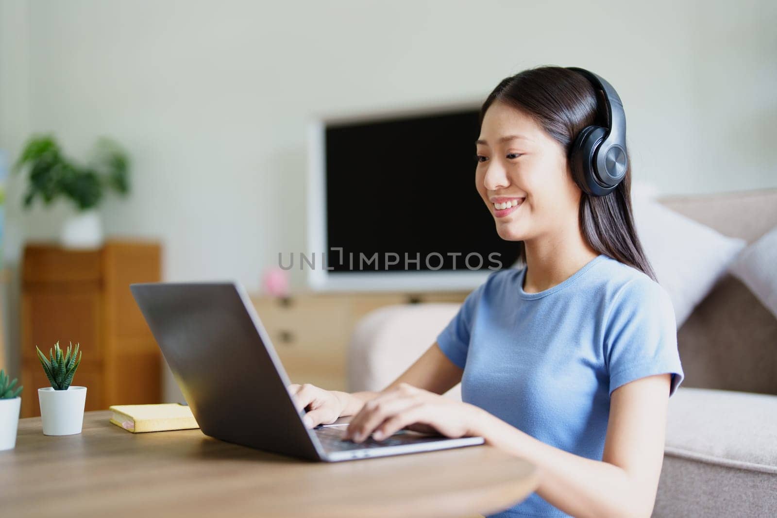woman wearing headphones on comfortable couch listening to using computer laptop and music