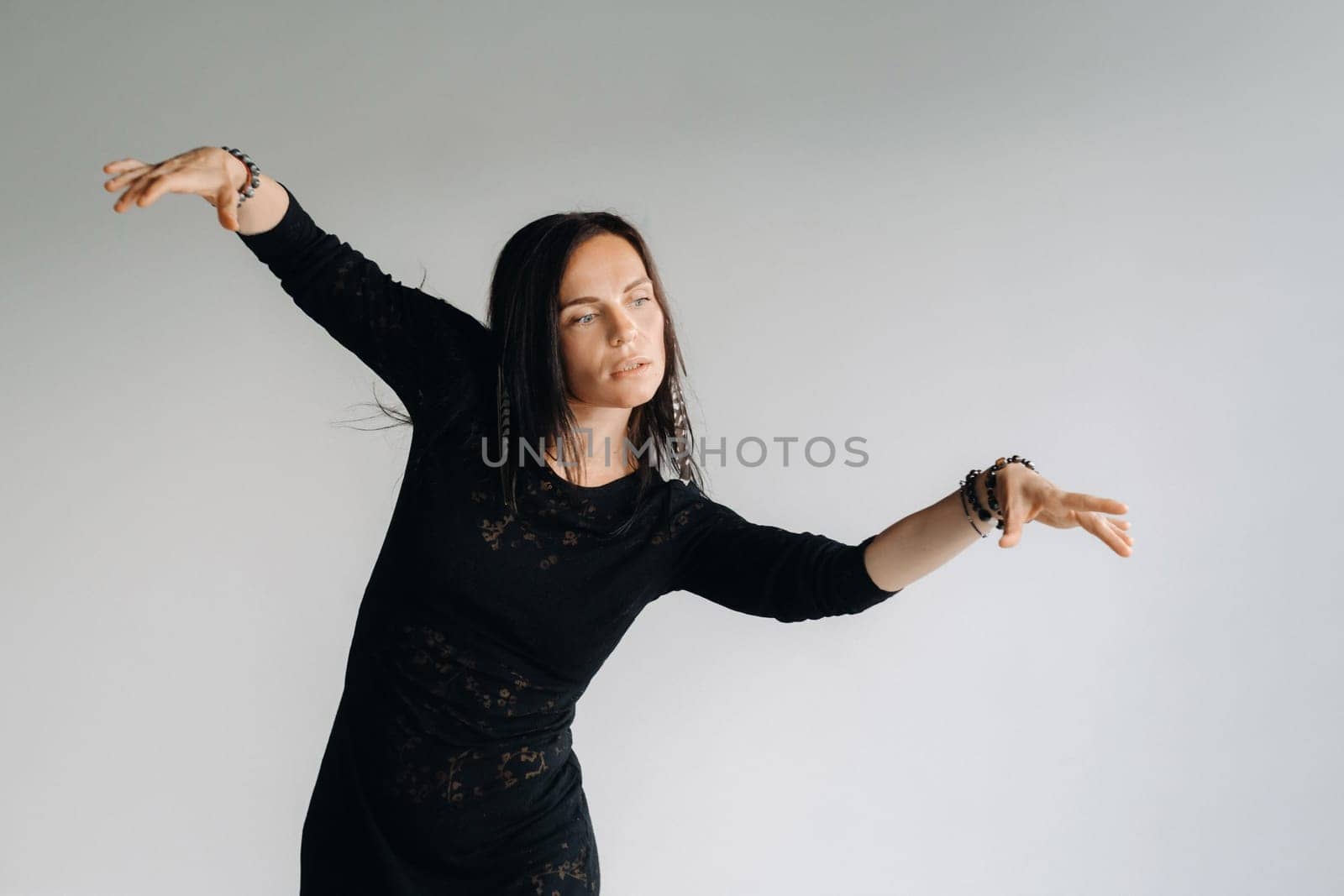 A girl in a black dress moves in a dance on a gray background. Dynamic dance by Lobachad