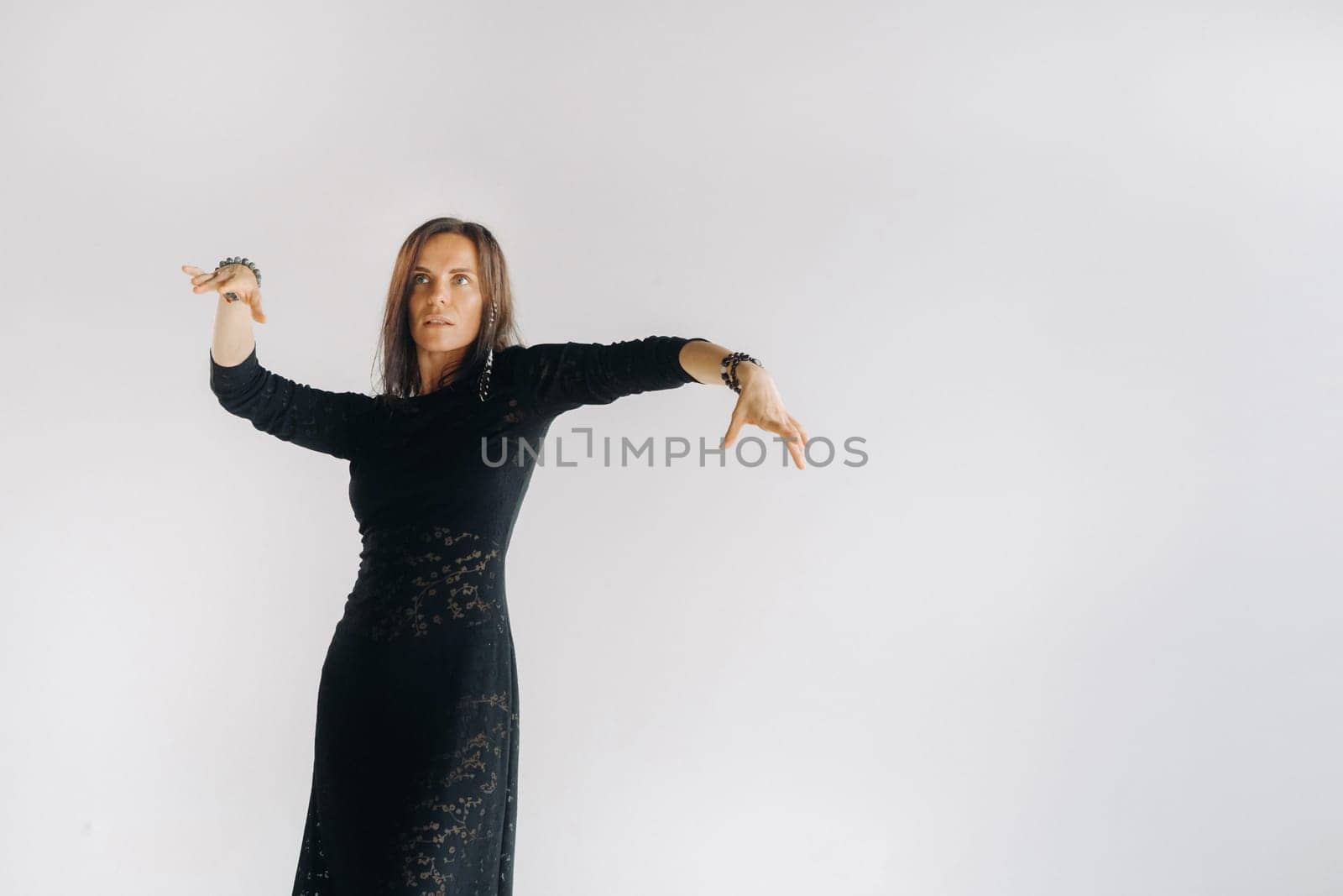 A girl in a black dress moves in a dance on a gray background. Dynamic dance by Lobachad