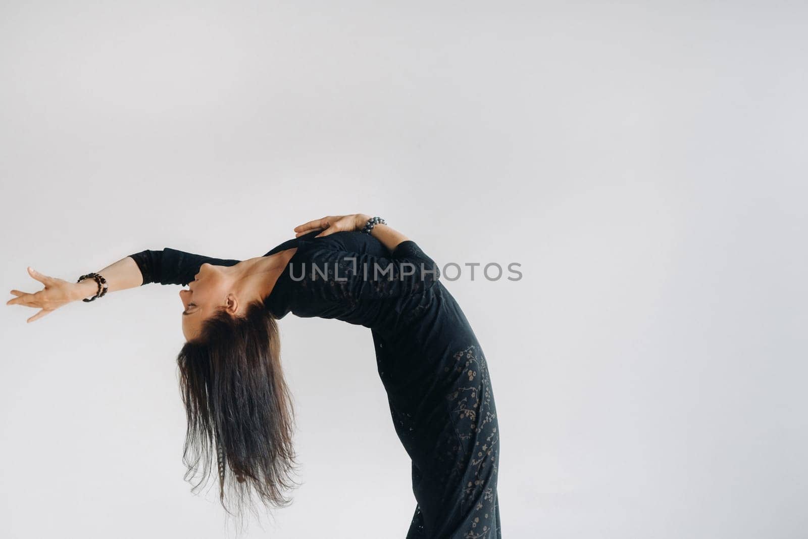 A girl in a black dress moves in a dance on a gray background. Dynamic dance by Lobachad