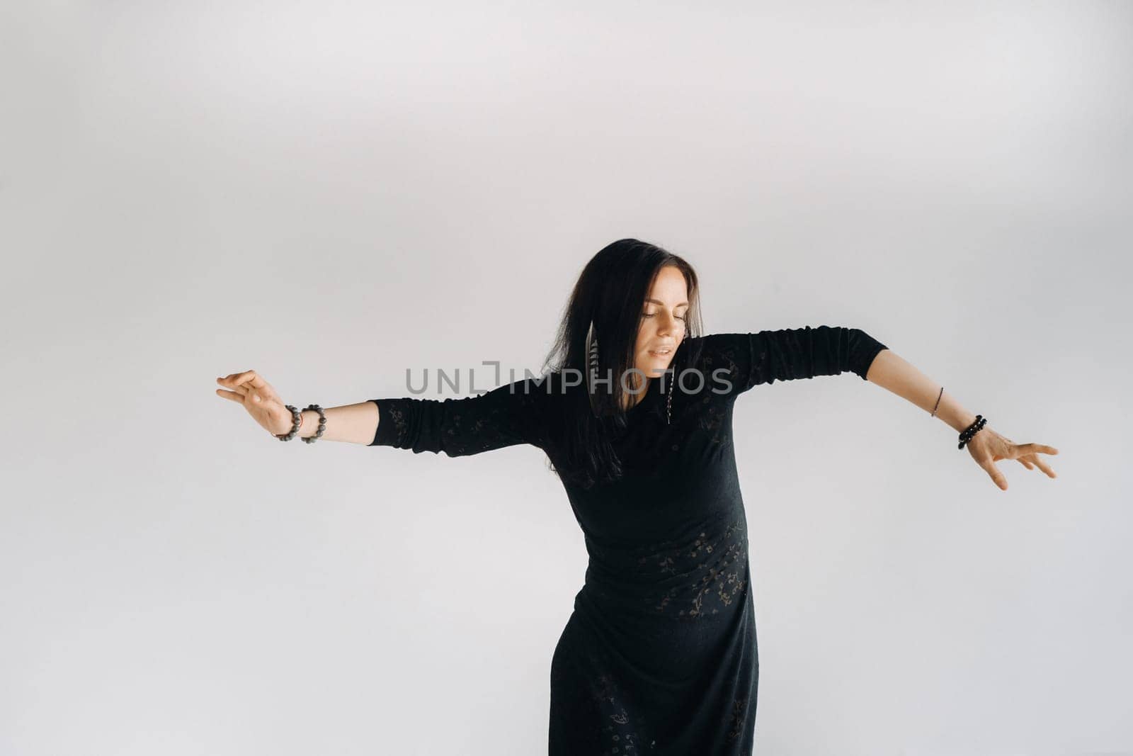 A girl in a black dress moves in a dance on a gray background. Dynamic dance by Lobachad