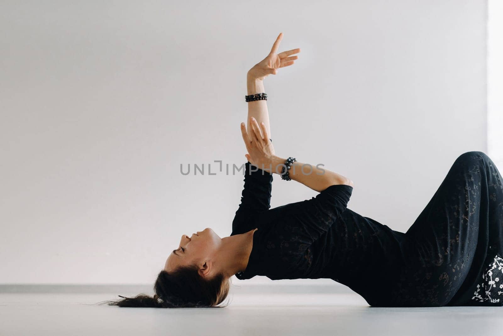 A girl in a black dress lying down moves in a dance on the floor. Dynamic dance.