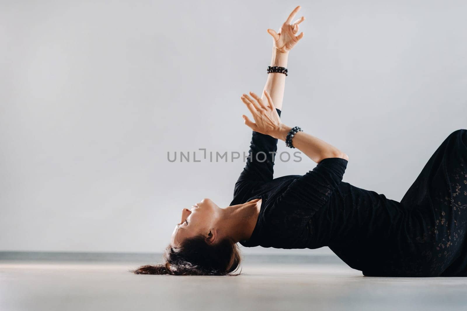 A girl in a black dress lying down moves in a dance on the floor. Dynamic dance.