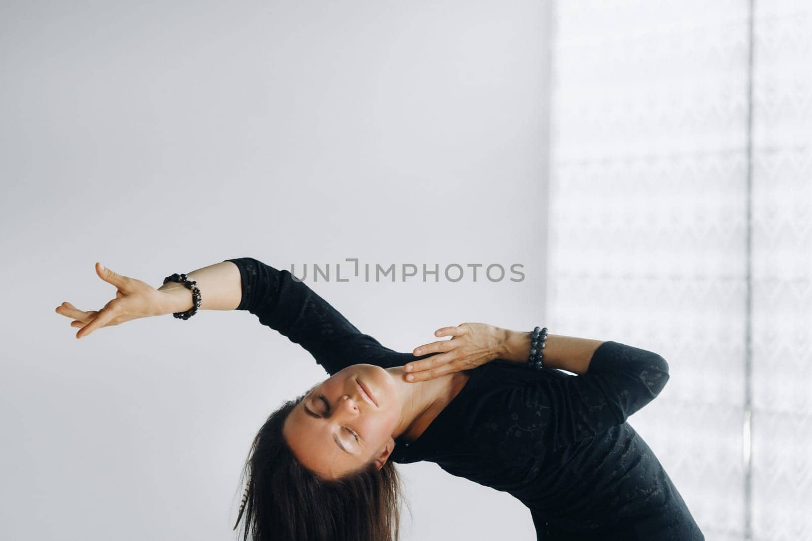 A girl in a black dress moves in a dance on a gray background. Dynamic dance,