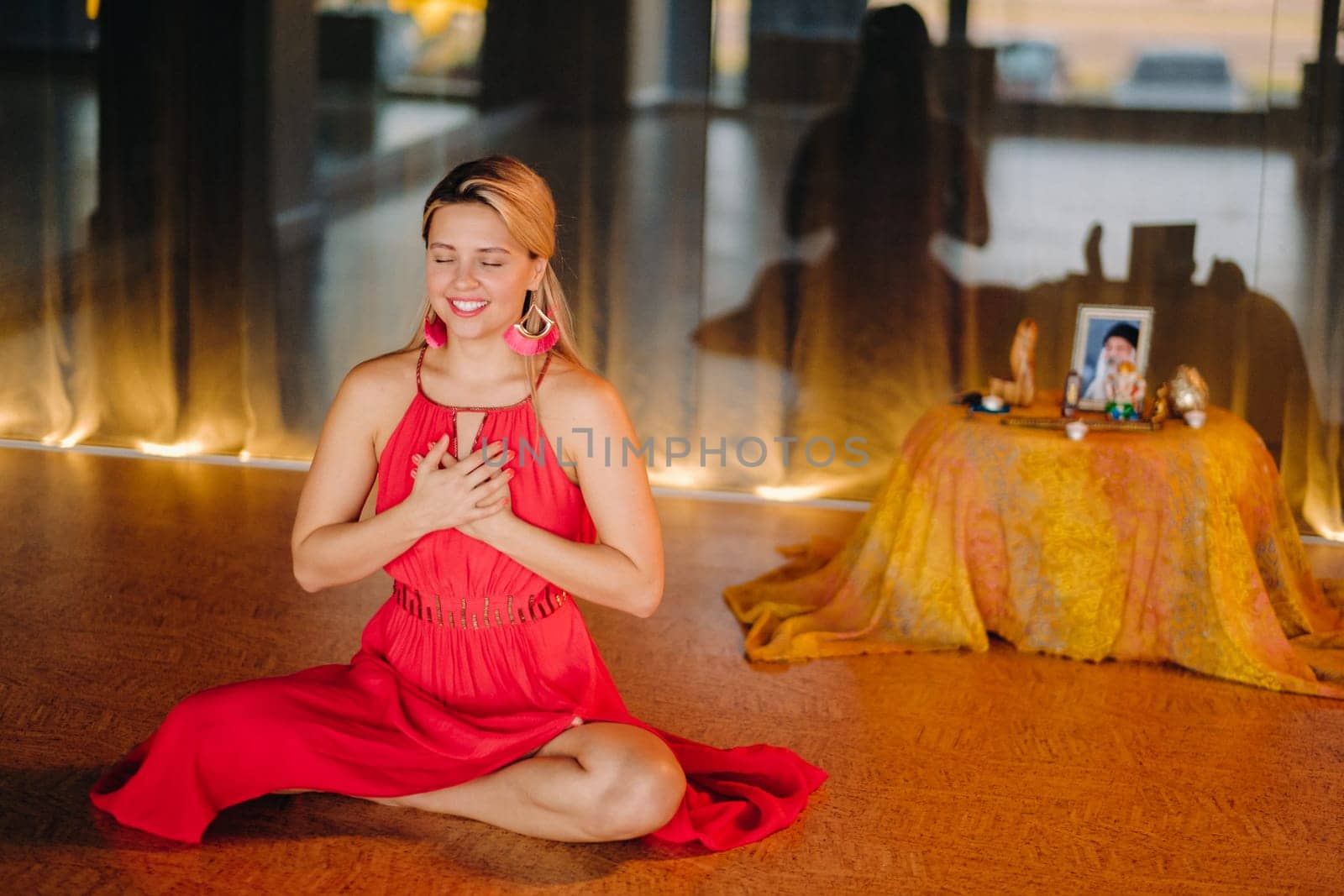 Meditation and concentration. a woman in a red dress, sitting on the floor with her eyes closed, is practicing medicine indoors. Peace and relaxation.