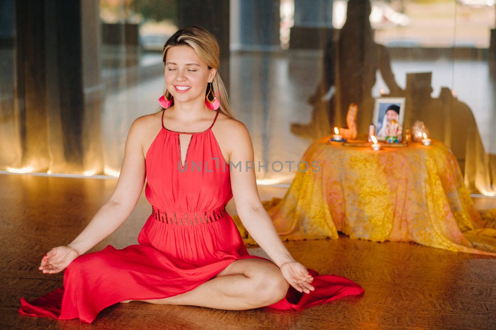 Meditation and concentration. a woman in a red dress, sitting on the floor with her eyes closed, is practicing medicine indoors. Peace and relaxation by Lobachad