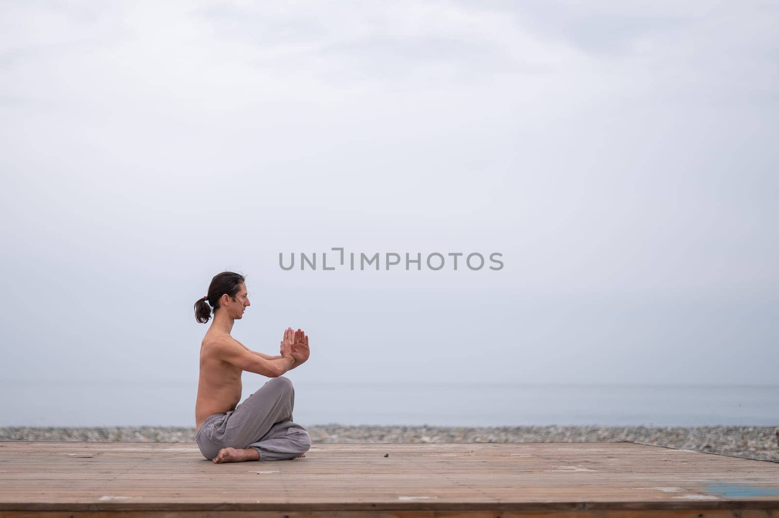 Caucasian man with naked torso practicing wushu on the seashore. by mrwed54