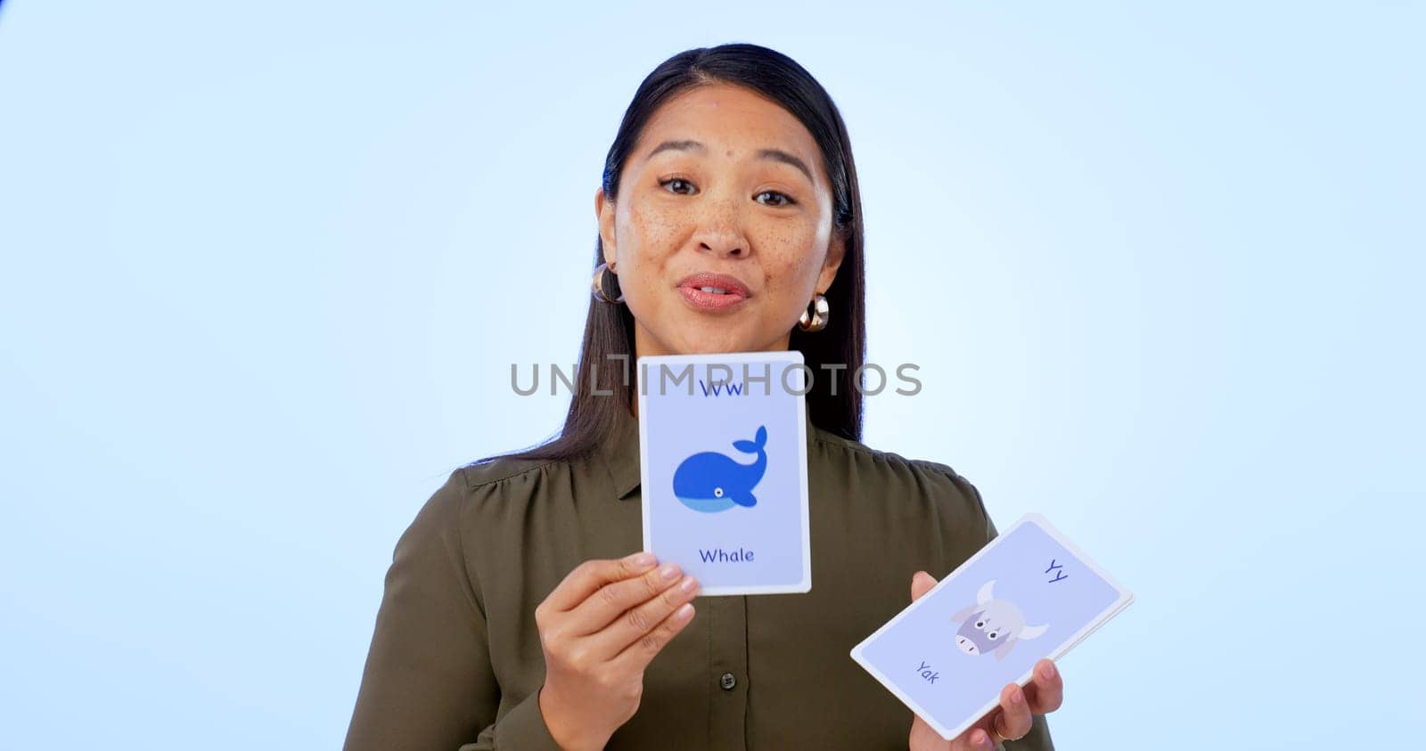 Asian woman, teacher and flash cards for teaching, education and isolated on studio background. Portrait, learning and show for development, elearning and study for english, animals and presentation.