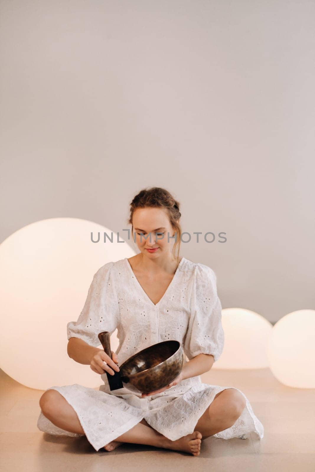 Portrait of a female yoga teacher playing a Tibetan bowl or singing a bell in the gym during a yoga retreat.