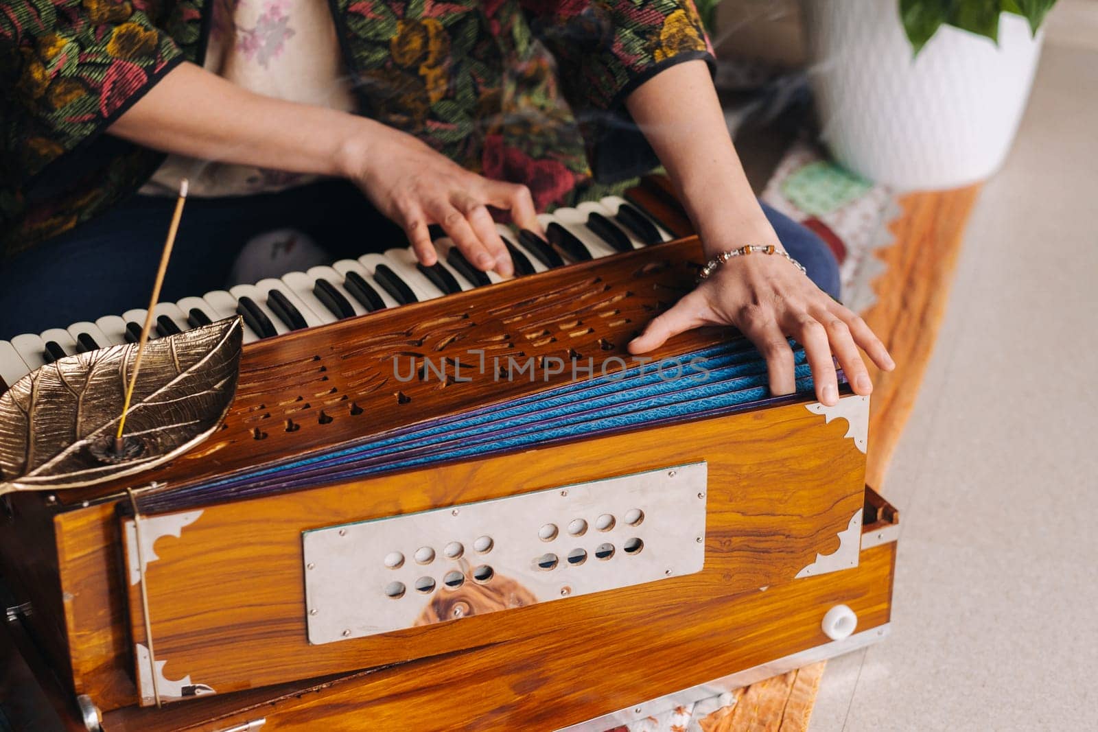 Hands of a woman sitting on the floor and playing the harmonium during the practice of kundalini yoga.