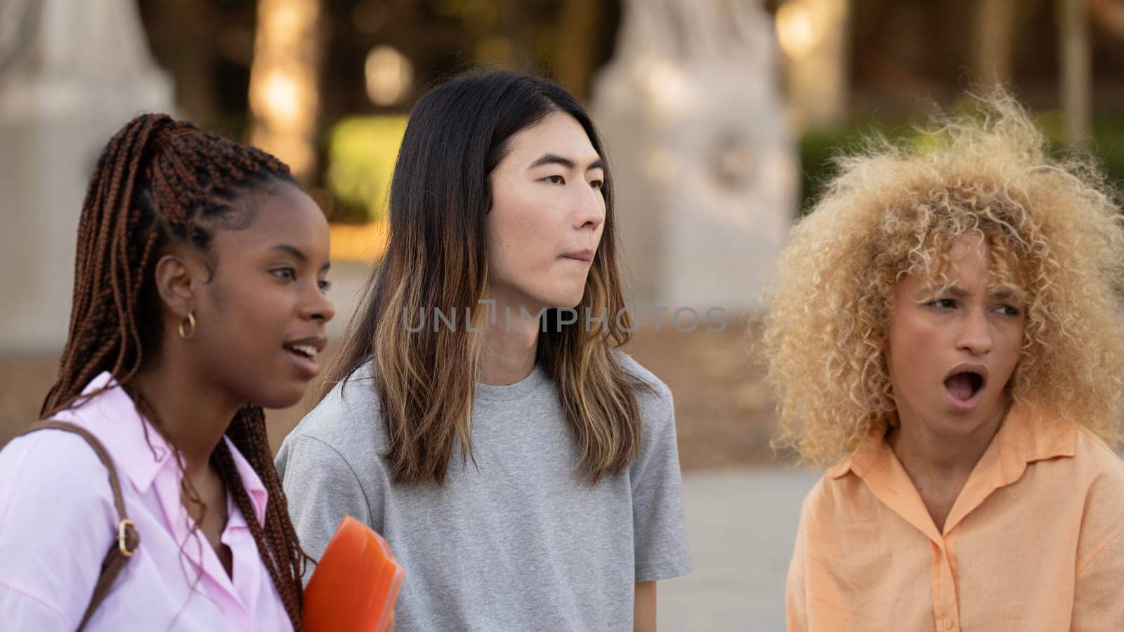 Multi ethnic Students looking away with expression of surprise in the face standing on a campus.
