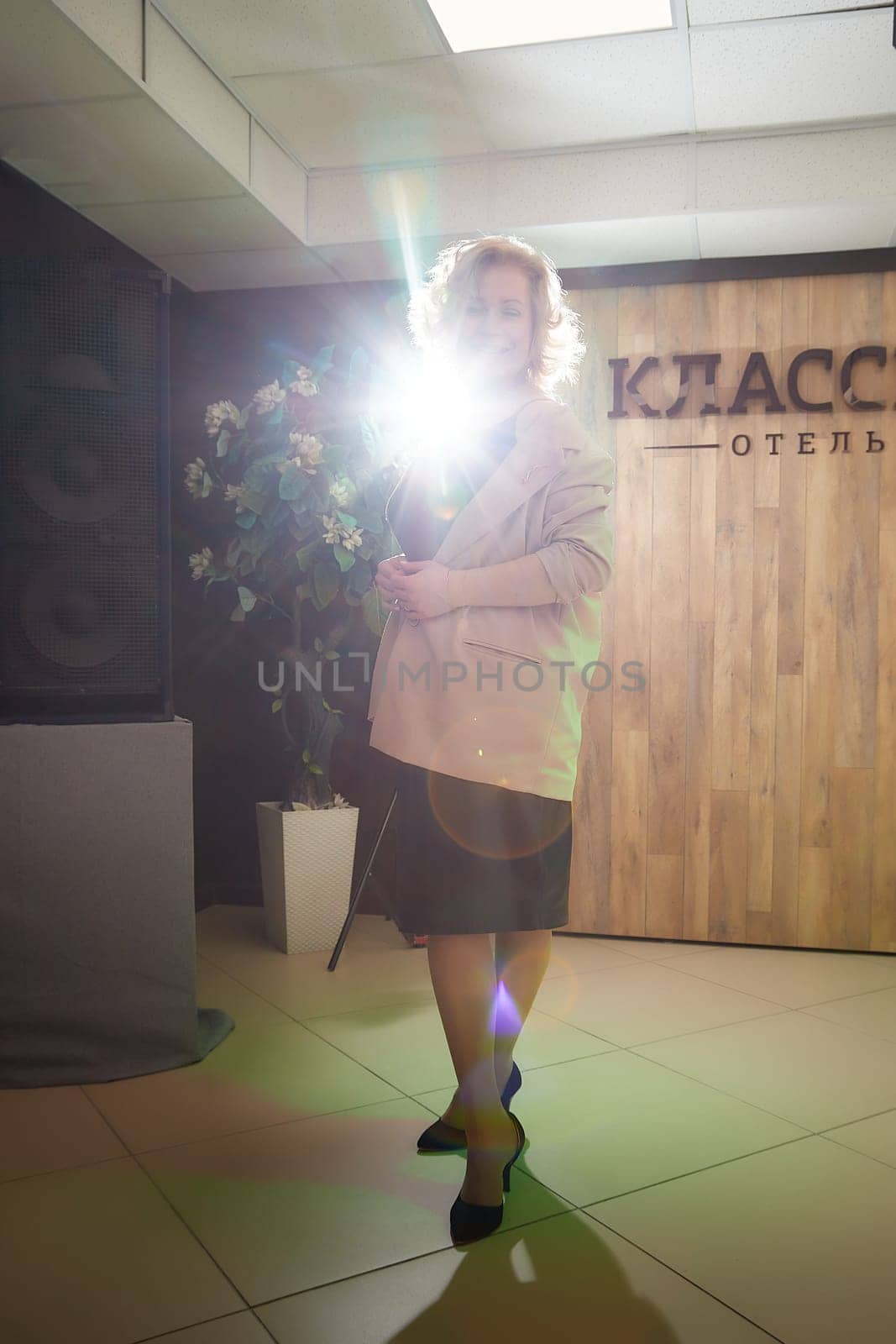 A girl, an adult woman in a costume on stage. An artist, an actress, a coach, a teacher, a presenter on stage with the light of spotlights or flashes. Paparazzi shooting of a famous person by keleny