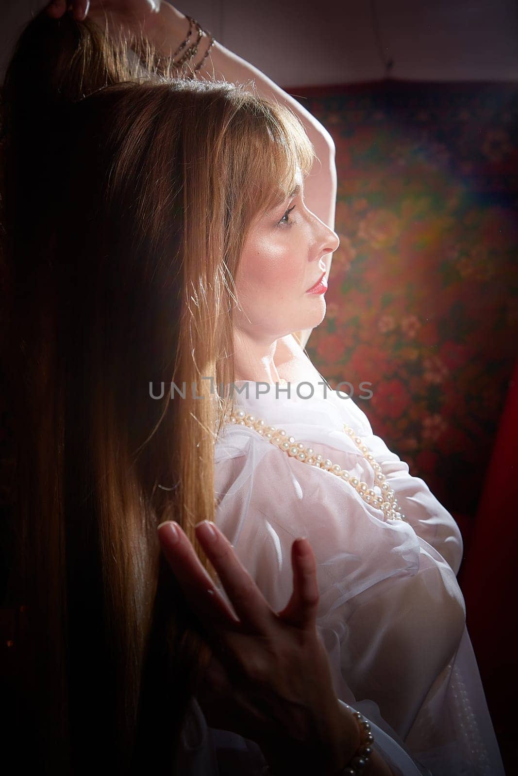 Beautiful European girl looking like Arab woman in red room with rich fabrics and carpets in sultan harem. Photo shoot of an oriental style odalisque. A model poses in sari as indian woman in india