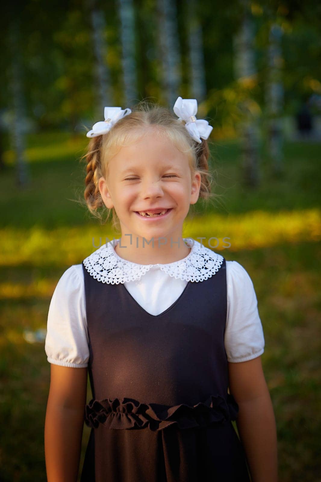 Little girl of elementary school student in modern school uniform outdoors. Female child schoolgirl going to school. Back to school in september 1