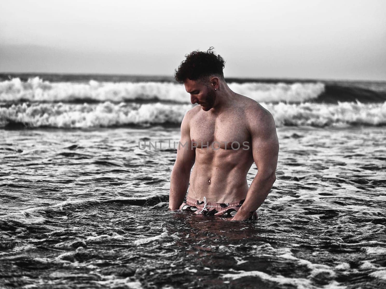 Handsome, hot young bodybuilder in the sea showing his muscular torso and arms - Muscular and fit young bodybuilder in the sea