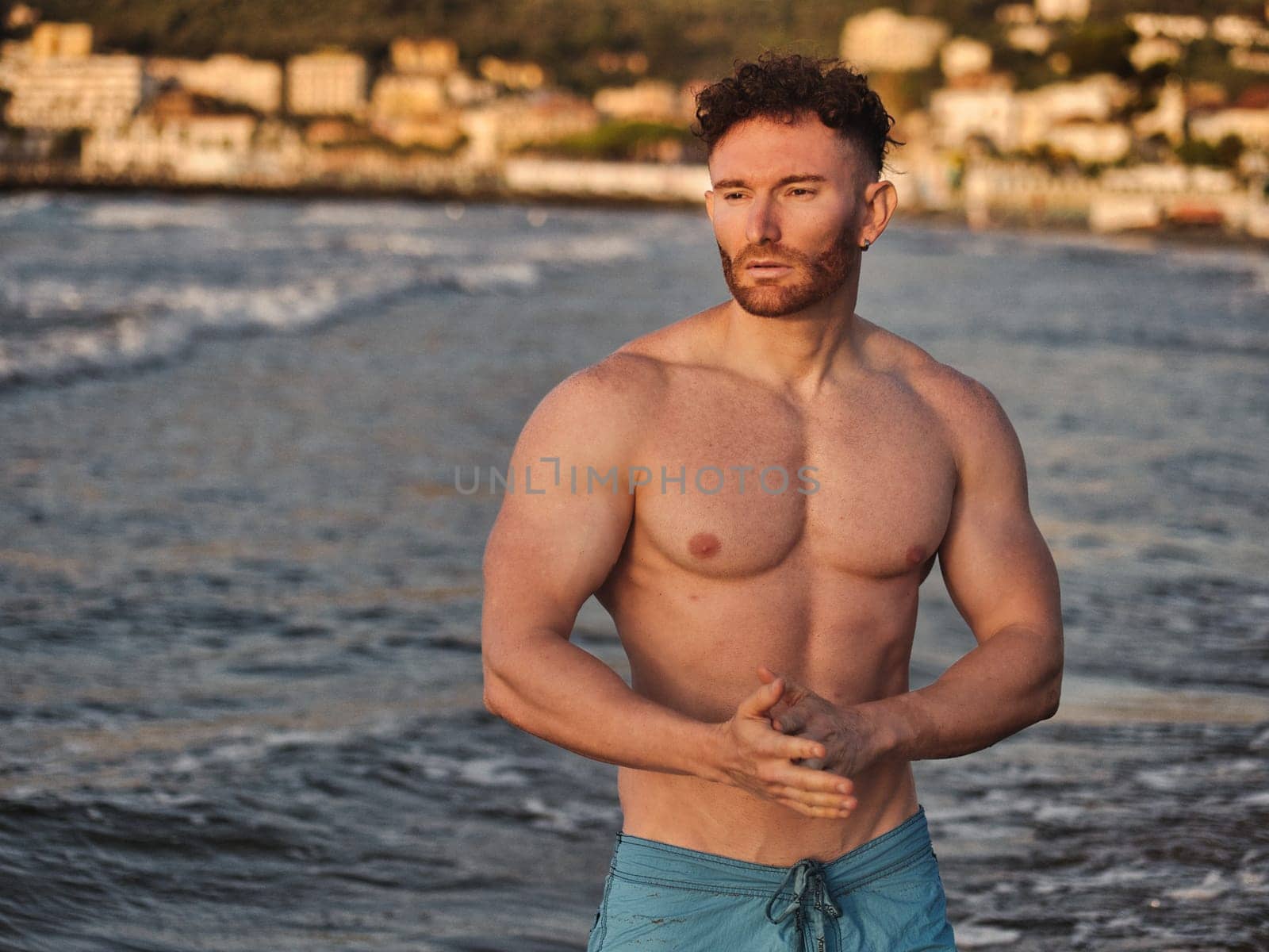 Muscular and fit young bodybuilder in the sea by artofphoto