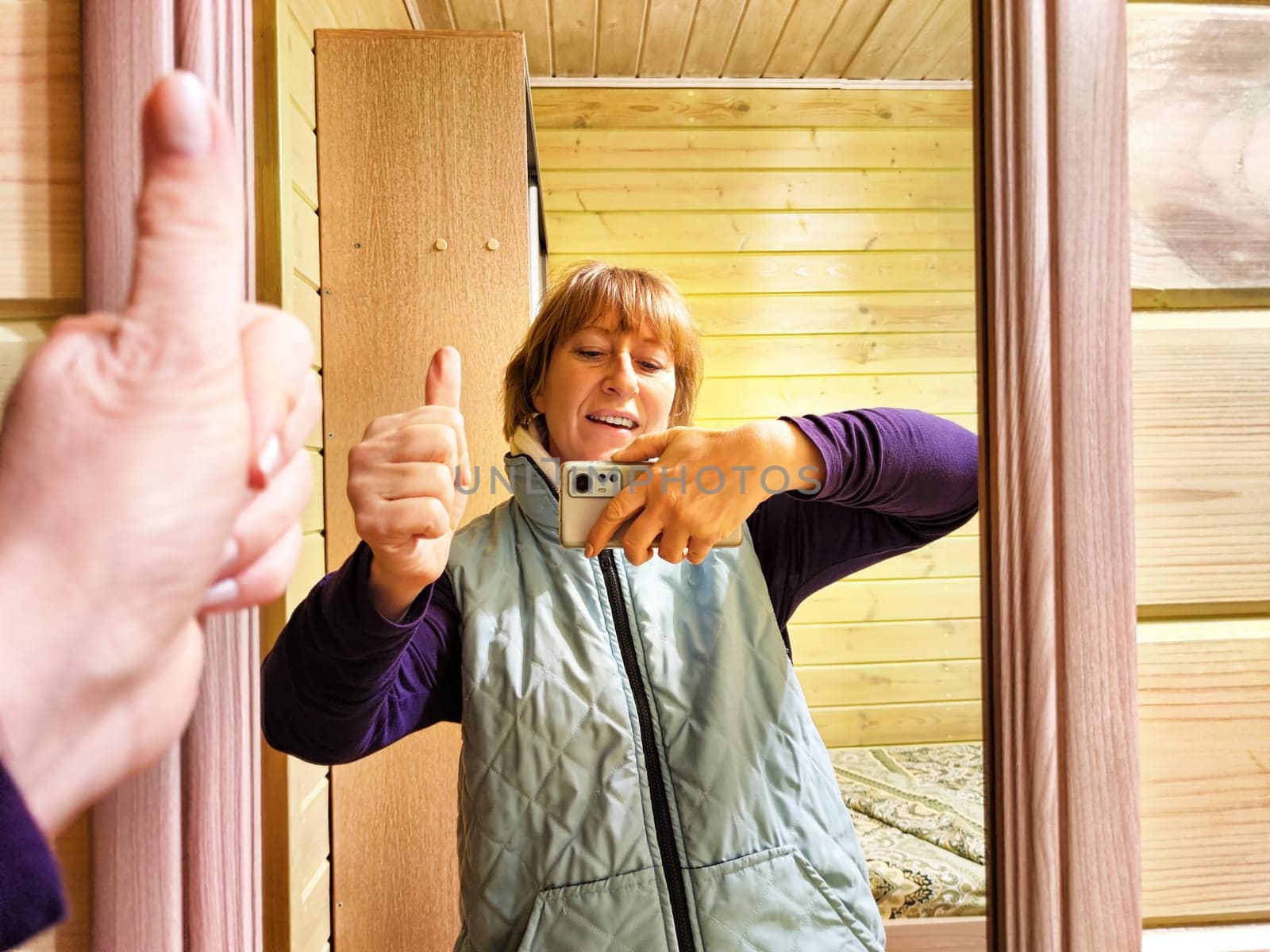 Middle-aged woman using smartphone for selfie and blogging. Female blogger poses in a photo. The girl admires herself in the mirror