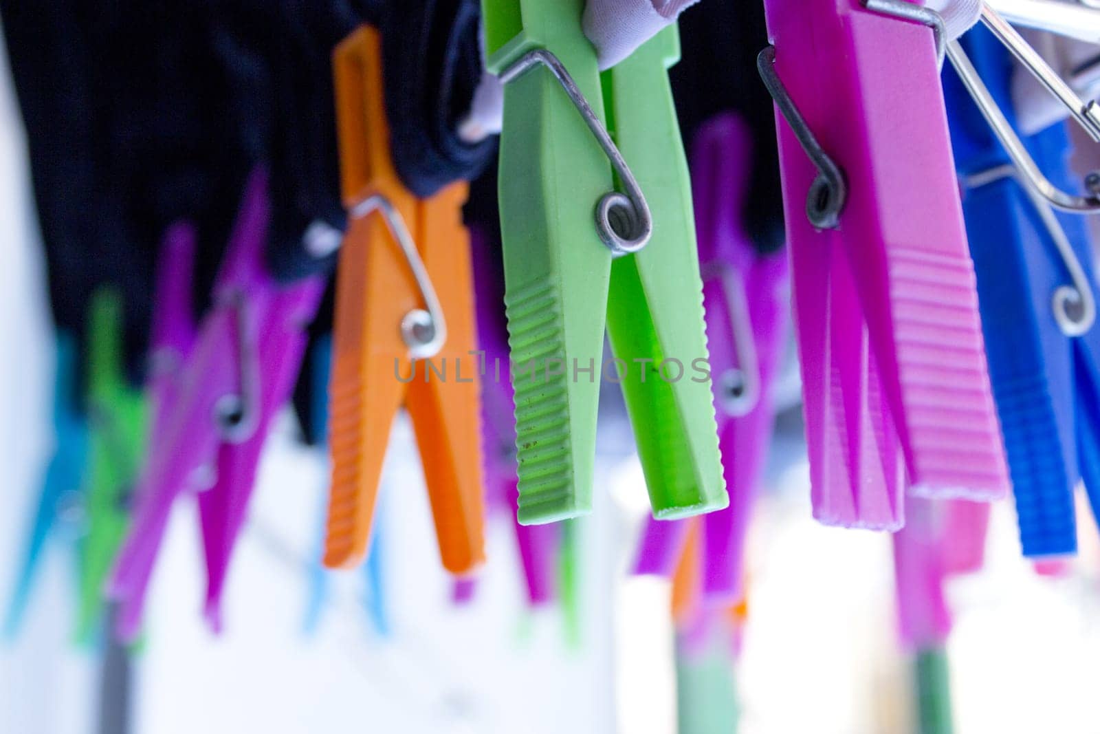 Clothespins holding clothes on clothesline. Various colors. No people