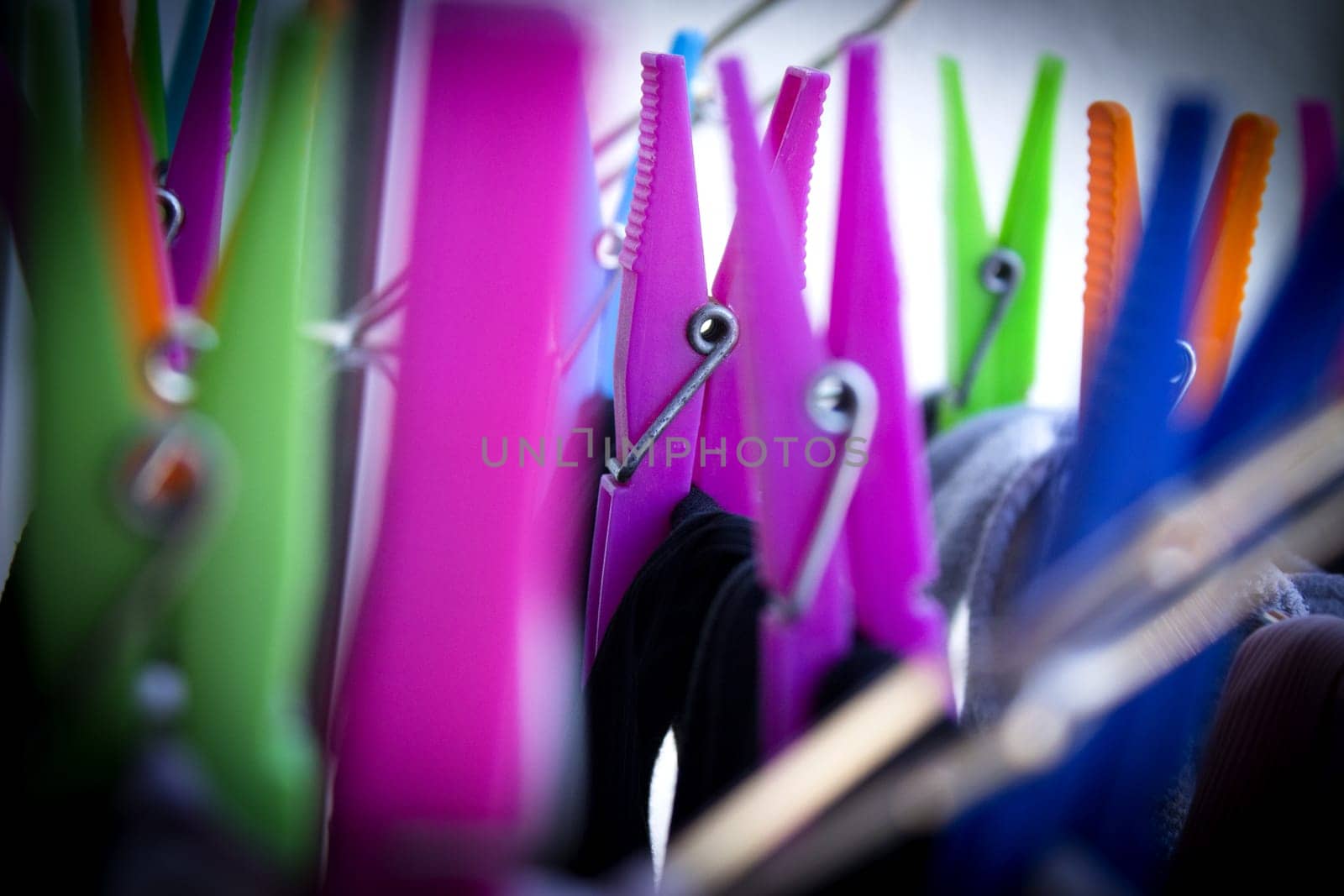 Clothespins holding clothes on clothesline. Various colors. No people