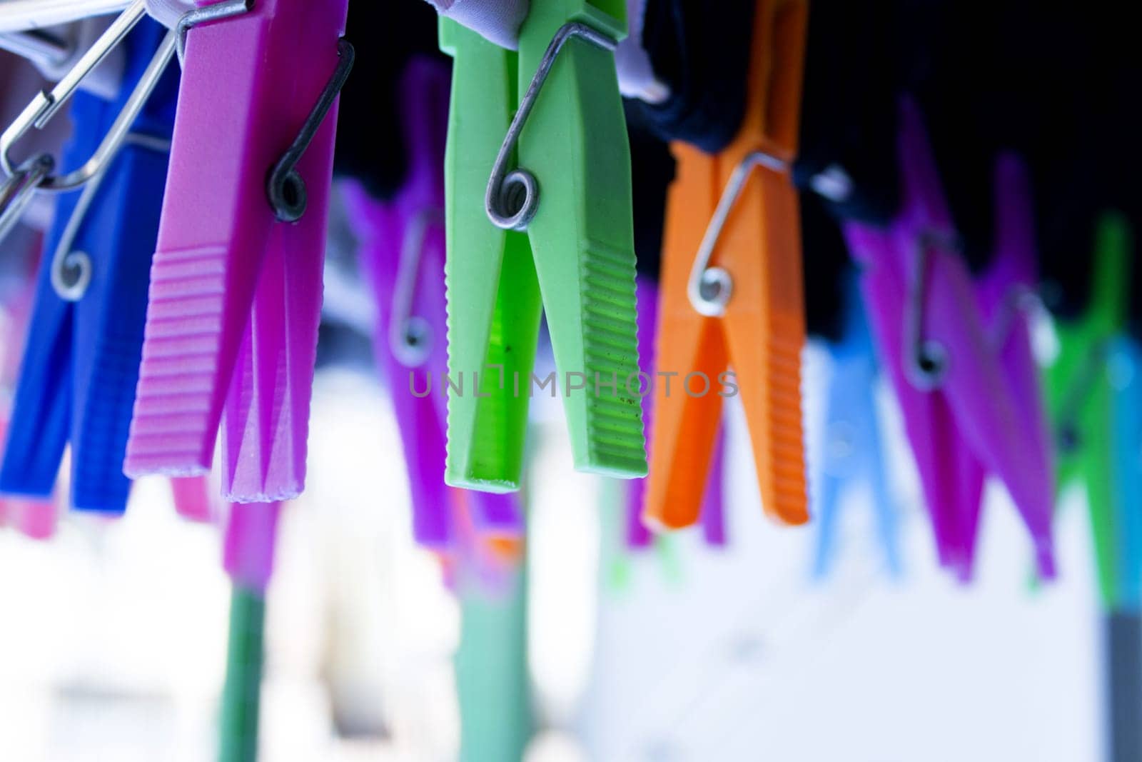 Clothespins holding clothes on clothesline. Various colors. by GemaIbarra