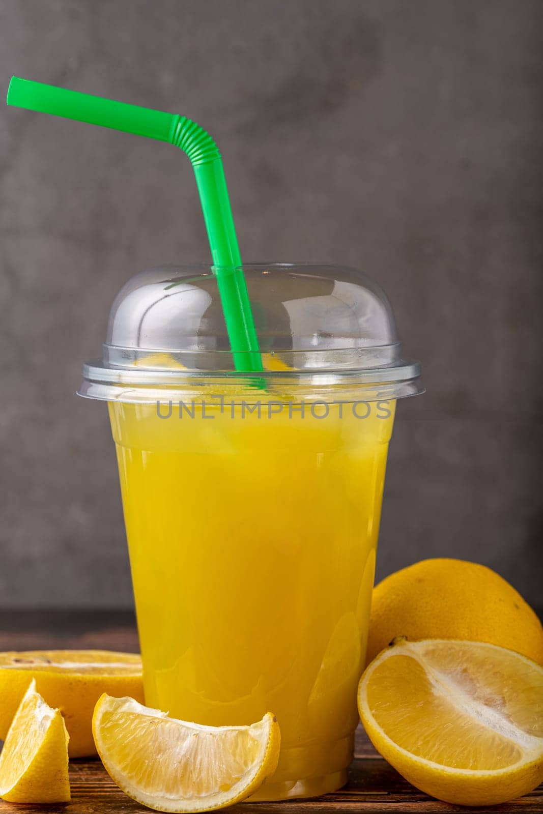 Iced lemonade in plastic glass on wooden table by Sonat
