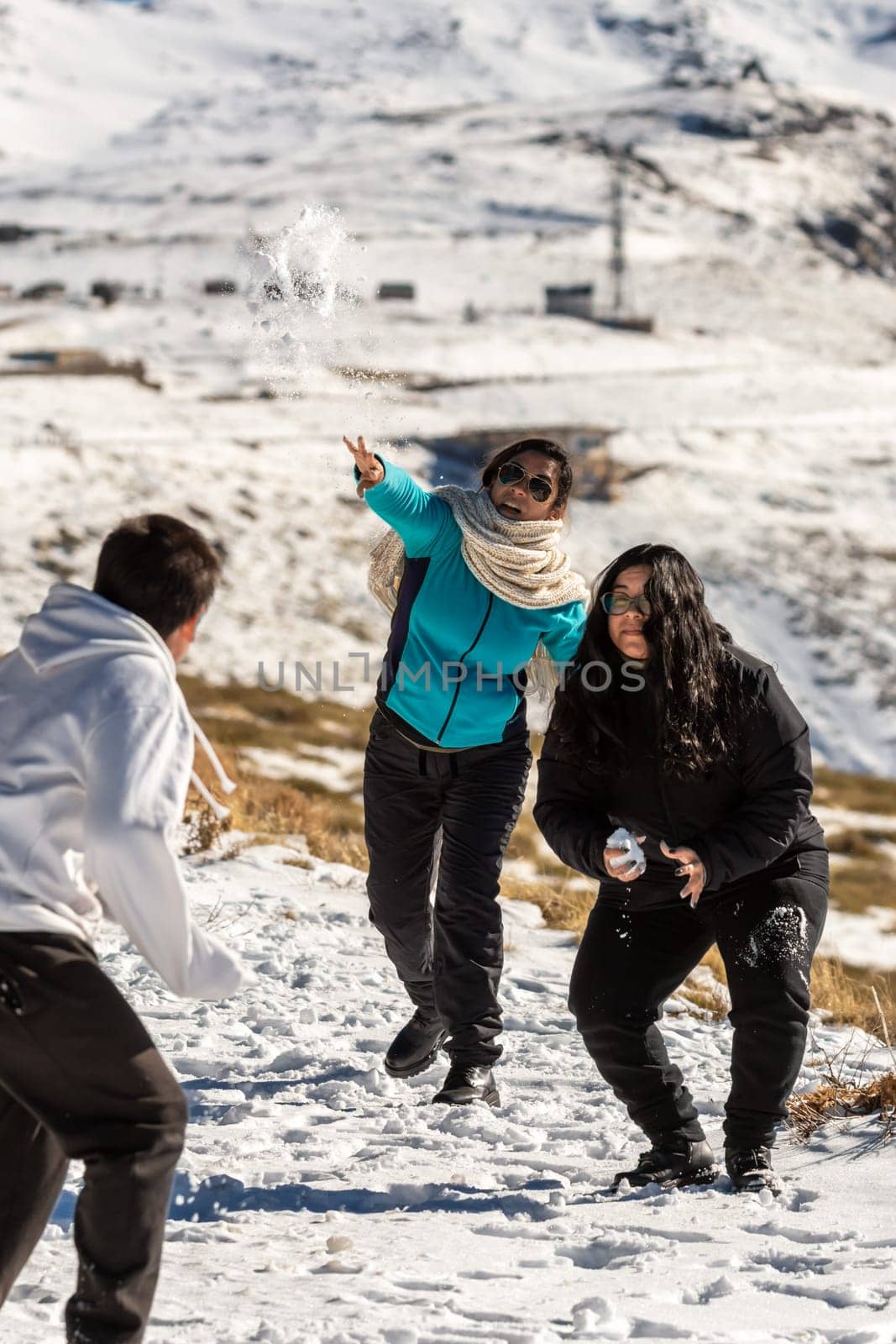 latin family at ski resort, in granada sierra nevada having fun throwing snowballs, playing on a sunny day,andalucia, spain,