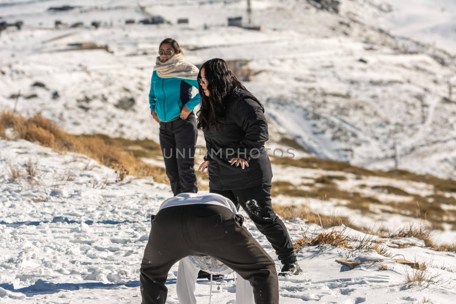 three young latin people playing in the snow in the mountains of sierra nevada