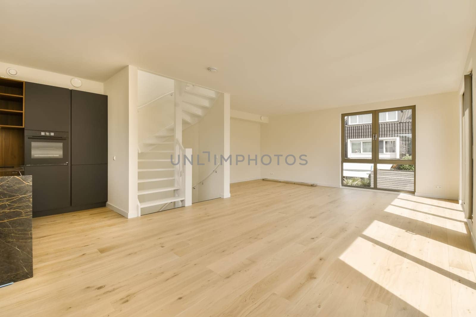 an empty living room with a staircase and a kitchen by casamedia